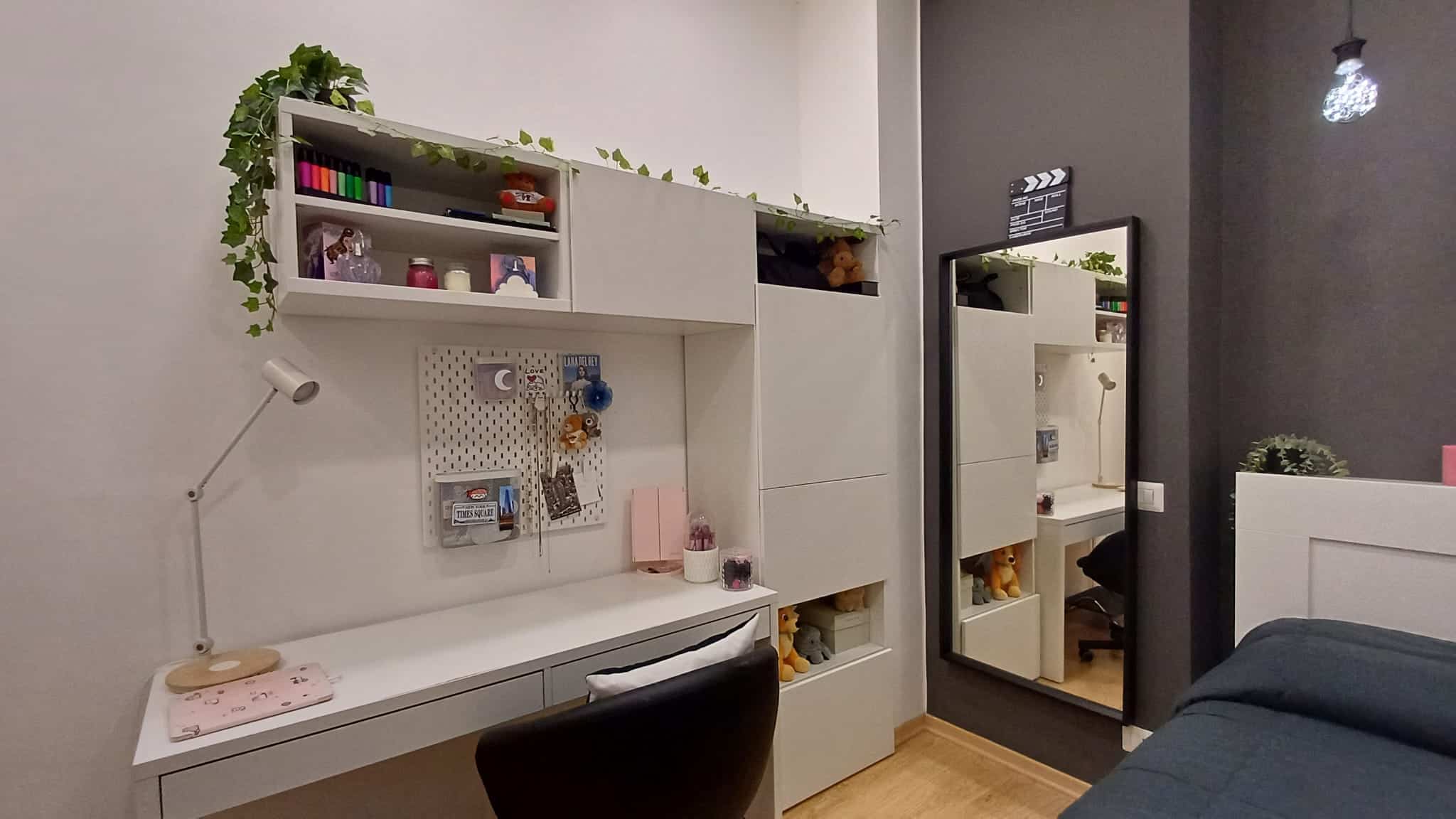 1. Scrivania moderna con scaffalatura bianca, decorata con piante e oggetti colorati, ideale per spazi di lavoro o studio in appartamenti di design.