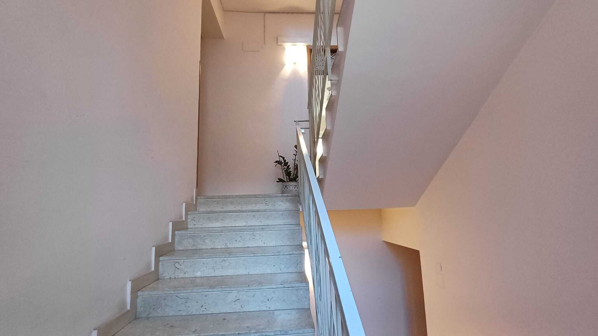 Elegante scala in marmo con ringhiera moderna, design raffinato e illuminazione soffusa, ideale per case di prestigio e immobili di alta qualità. Perfetta per valorizzare l'ingresso di ogni casa raffinata.