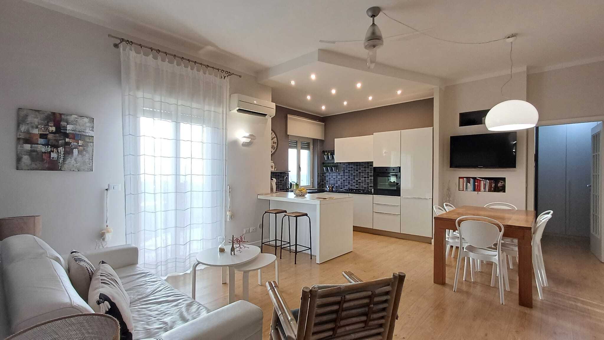 Appartamento moderno con cucina open space, soggiorno luminoso e zona pranzo, arredamento elegante e spazi accoglienti, ideale per vivere al meglio l'ambiente domestico.
