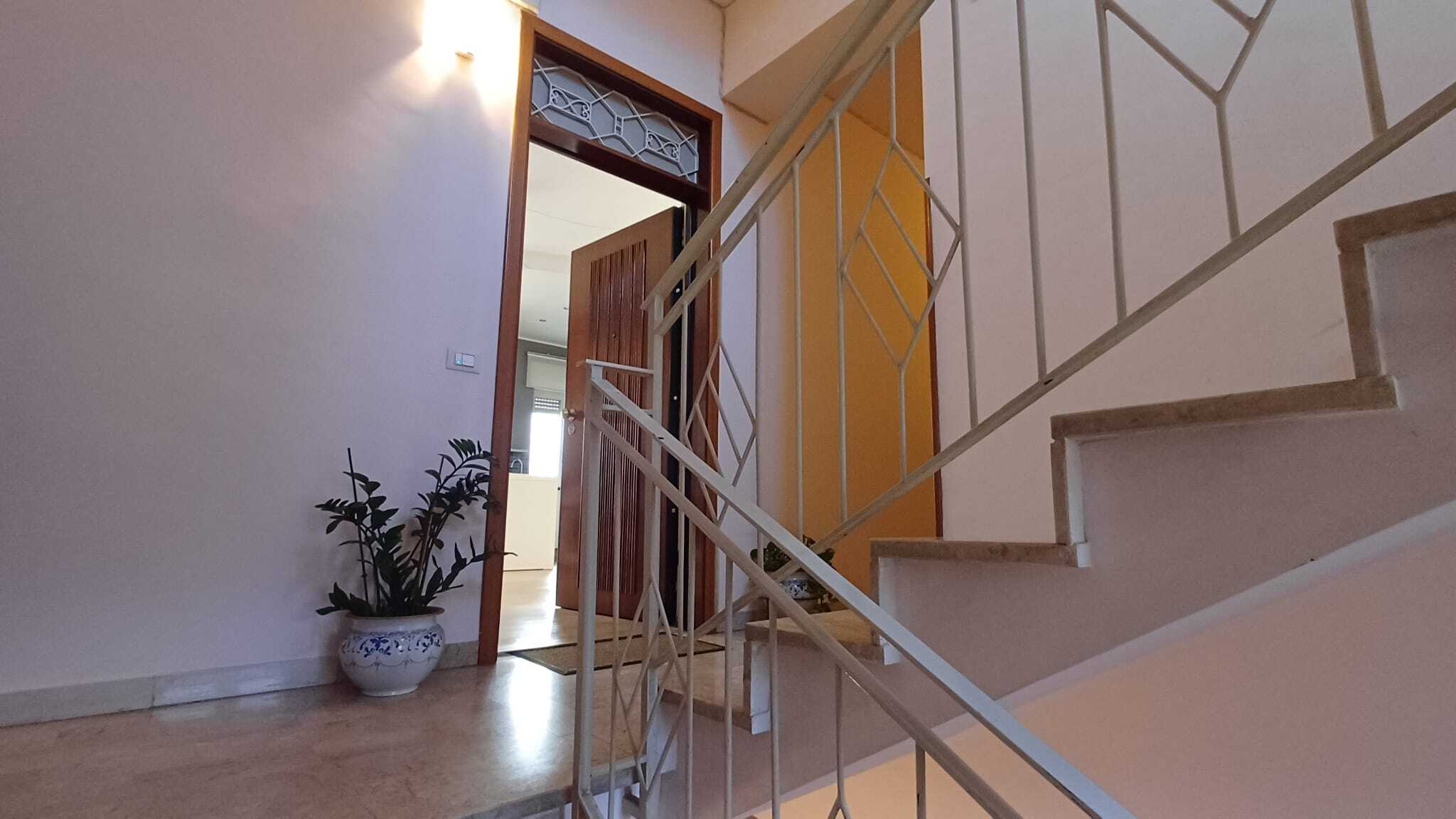 Ampio ingresso di casa con scaletta, porta in legno e pareti chiare, luminosa e accogliente, ideale per abitazione moderna con servizi di intermediazione immobiliare NextCasa.
