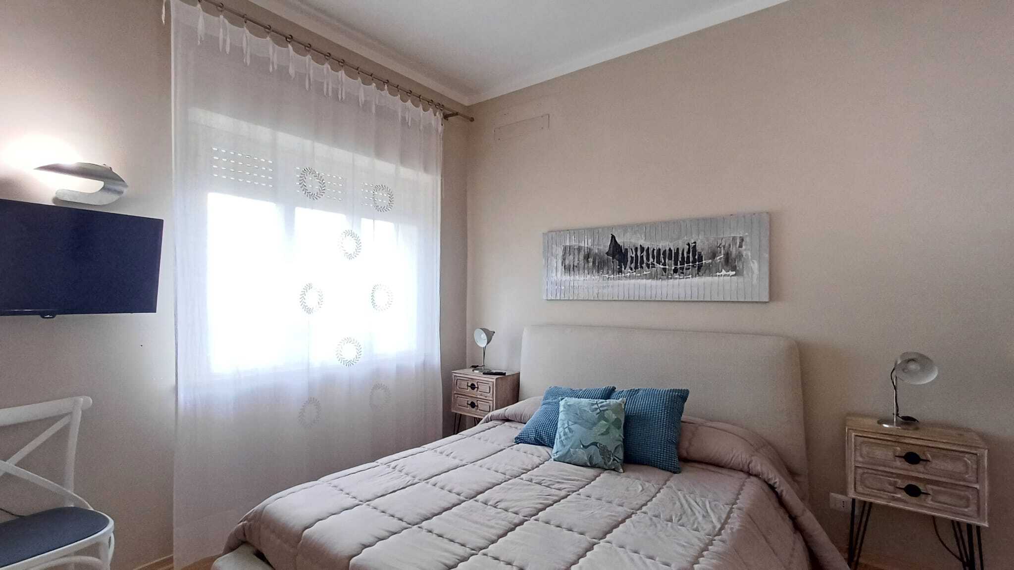 Appartamento luminoso con camera da letto elegante, arredamento moderno, tende trasparenti e dettagli decorativi di classe, ideale per investimenti immobiliari e affitti di qualità.