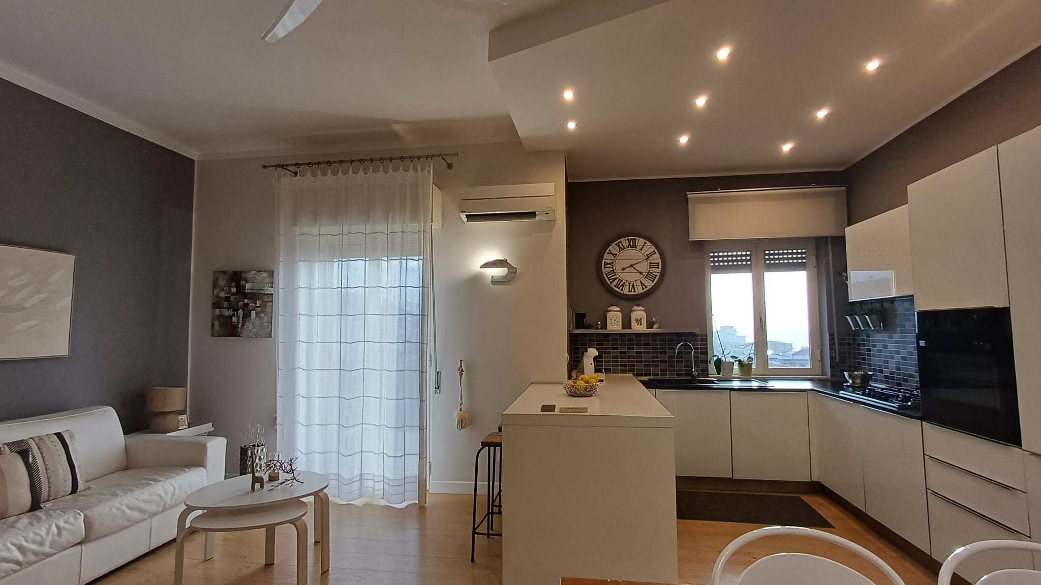 Spazi abitativi moderni e luminosi, cucina a vista con elettrodomestici all'avanguardia, area living con divano e decorazioni eleganti, ideale per vivere in comfort e stile.