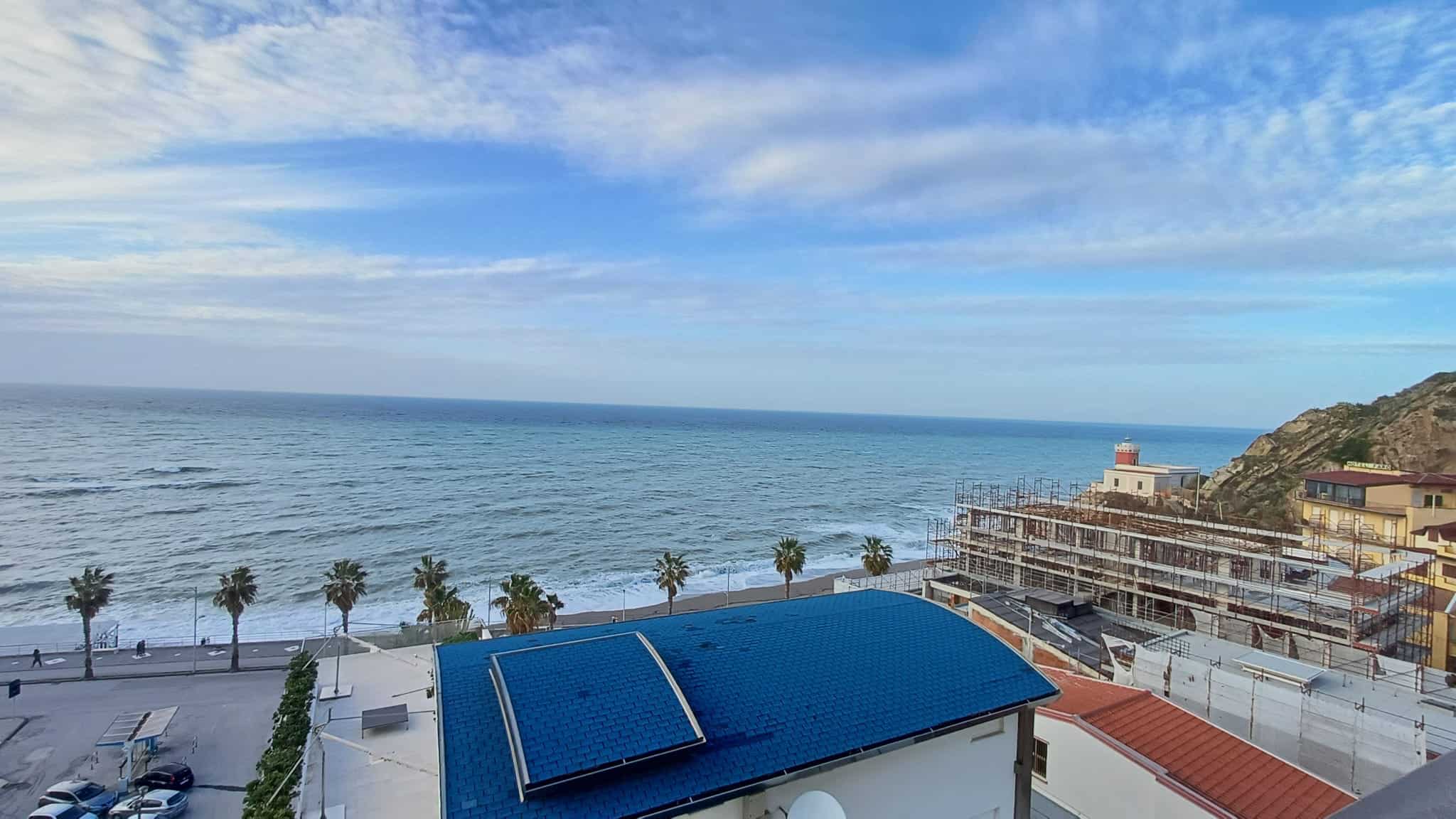 Vista mare sulla costa con scogliera e costruzioni in fase di ristrutturazione, by NextCasa, immobiliare specializzato in case fronte mare e proprietà di lusso in Italia.