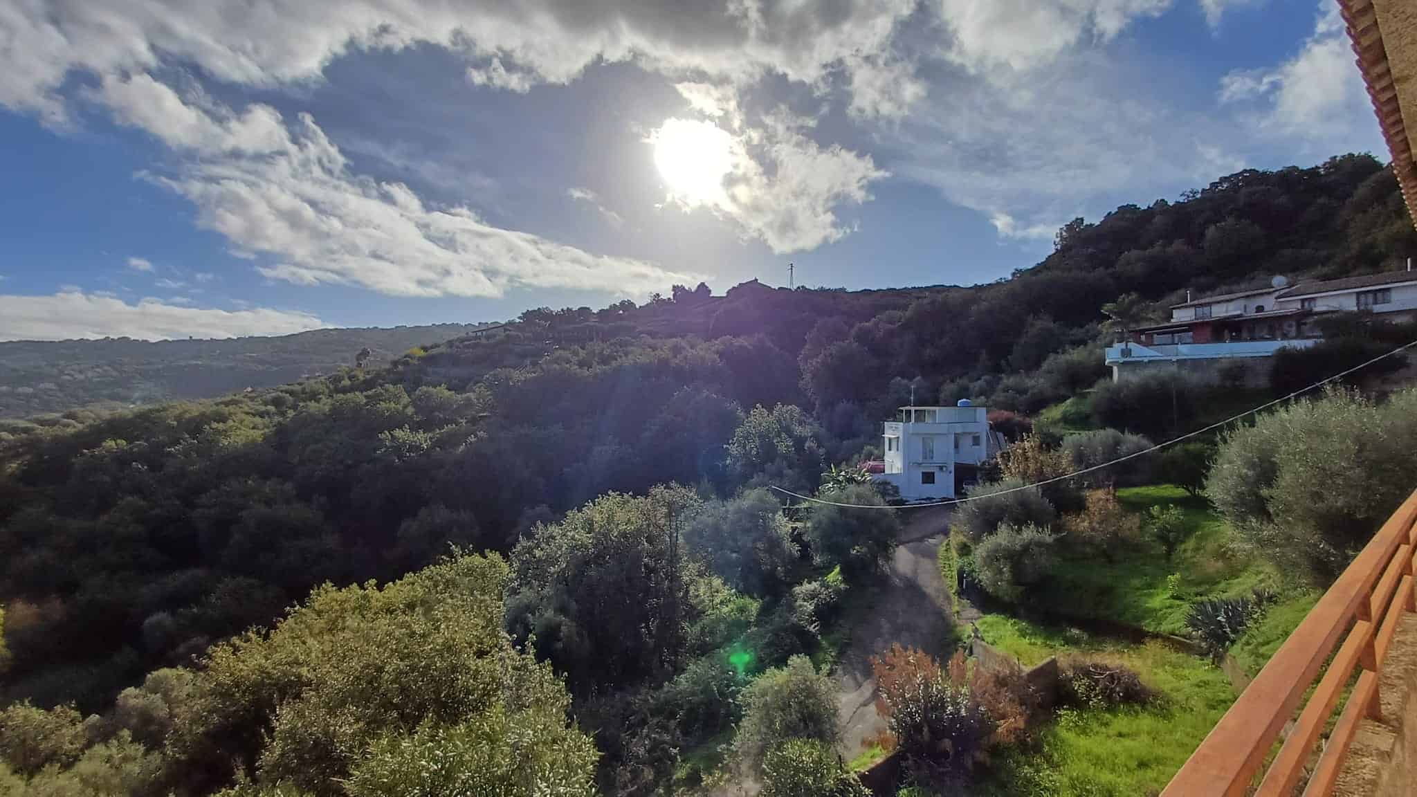 Paesaggio montano con natura incontaminata, case moderne e cielo soleggiato, ideale per investimenti immobiliari in zone panoramiche, vista mare, tranquillità e comfort.