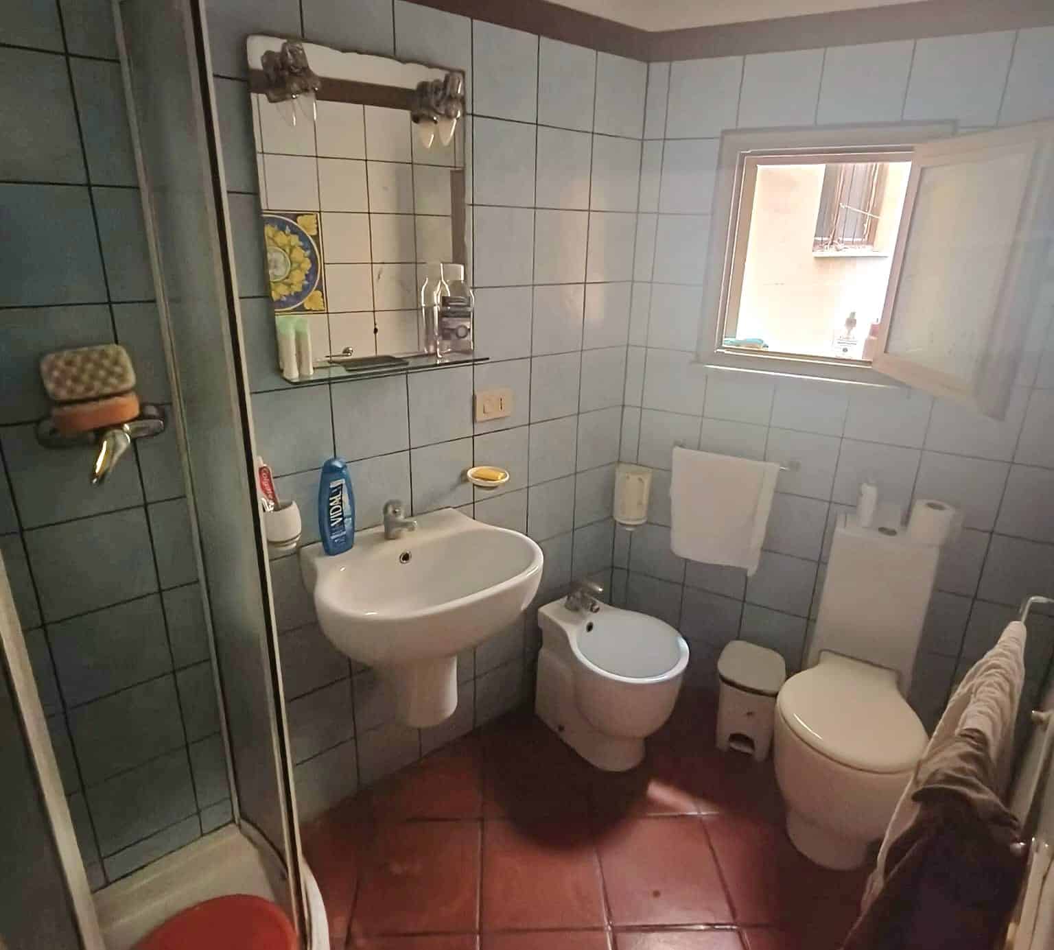 1. Bagno di casa con lavabo, WC e bidet, ambiente funzionale, finestra naturale, piastrelle azzurre, ideale per soluzione abitativa confortevole.