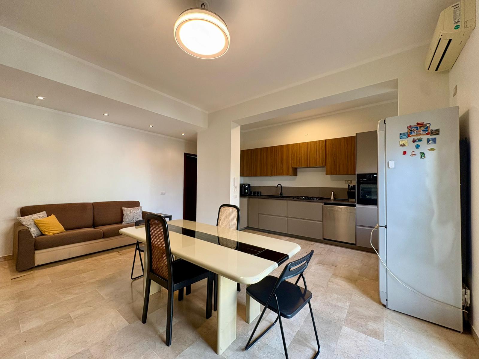 Appartamento moderno con cucina attrezzata, zona pranzo e soggiorno in stile minimalista, ideale per vivere con comfort e stile.