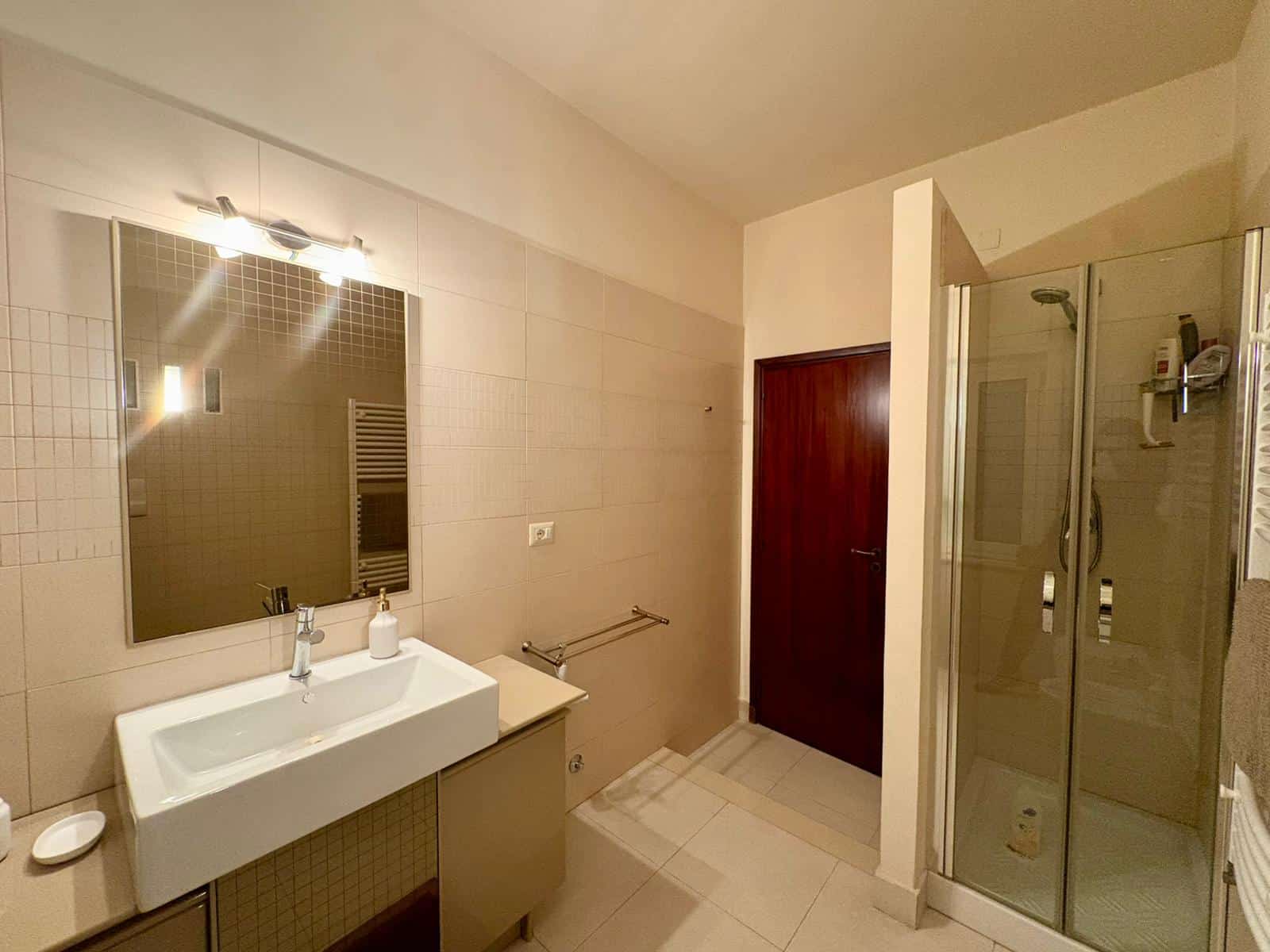 Lavabo e specchio in bagno moderno con doccia in vetro, comfort e stile. Perfetto per case e appartamenti di lusso, valorizza l'ambiente bagno con eleganza e praticità. Ottimale per ricerche immobiliari e ristrutturazioni.