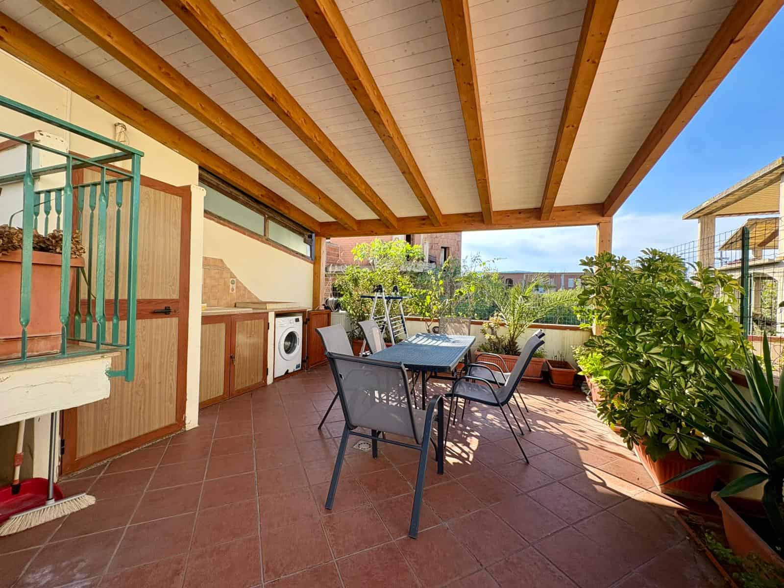 Terrazza con arredi esterni, piante verdi e cucina in posizione tranquilla, ideale per relax e convivialità in un contesto residenziale a NextCasa.