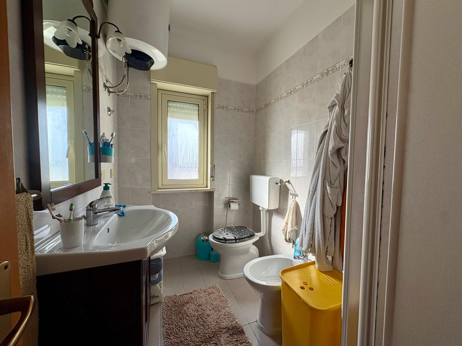 Lavabo e specchiera con luci, finestra e sanitari in bagno di casa NextCasa in Italia.