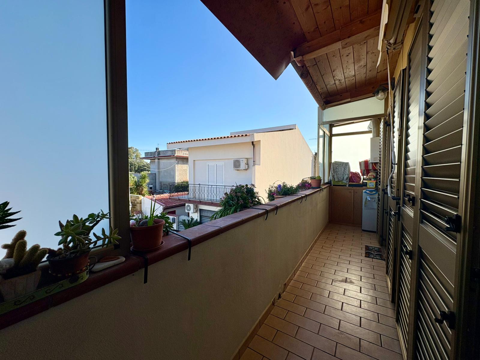 Vasto balcone con piante e vista sul quartiere residenziale, ideale per relax e arredamento esterno.