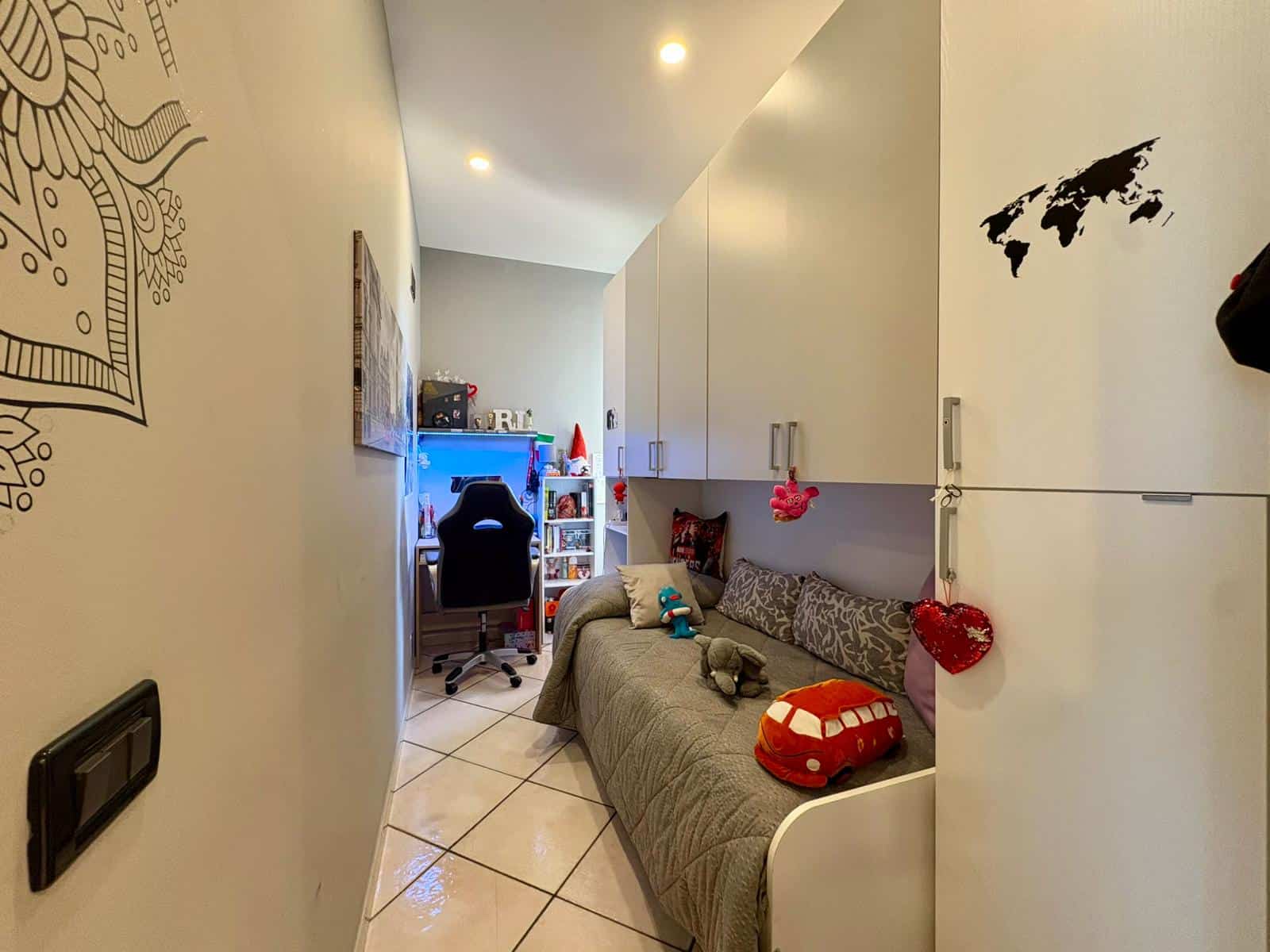 Letto a scomparsa con armadiature pannellate, angolo studio con scrivania e sedia ergonomica, decorazioni e giochi per bambini, soluzione ideale per vivere in modo funzionale e comodo.
