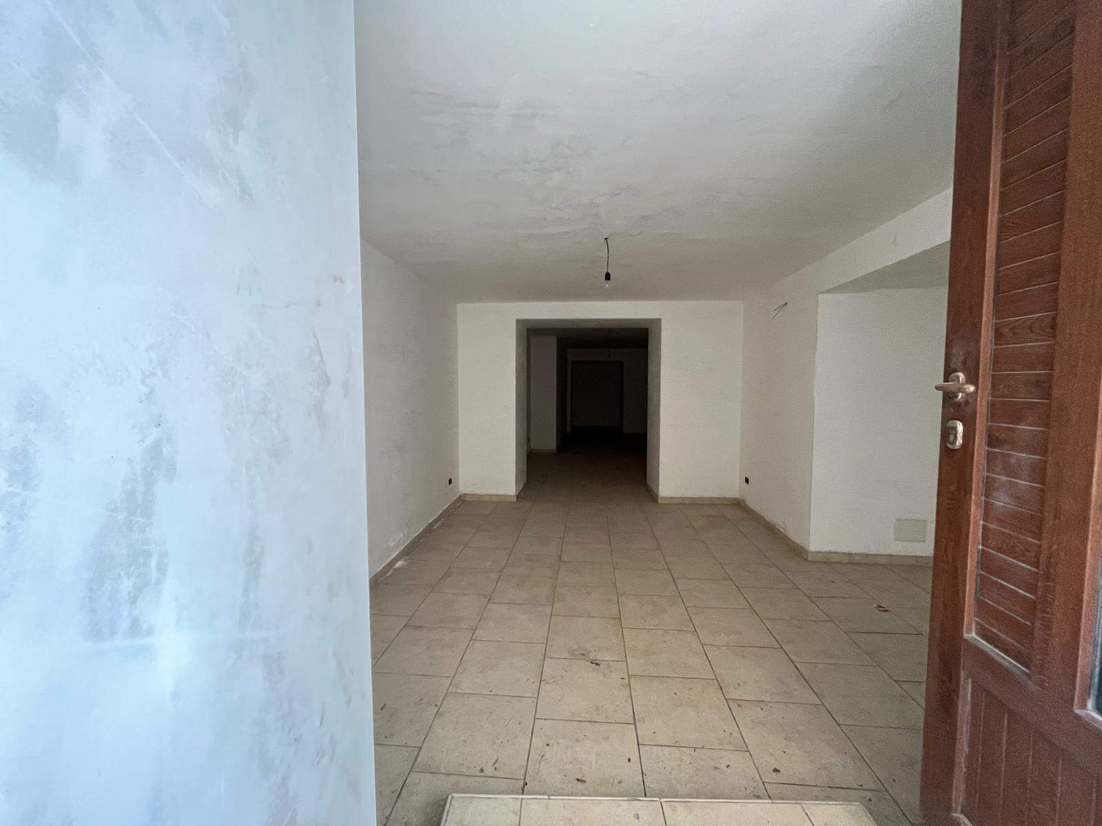 Interno di un appartamento in fase di ristrutturazione con pareti bianche e pavimento in piastrelle beige, pronto per essere arredato.