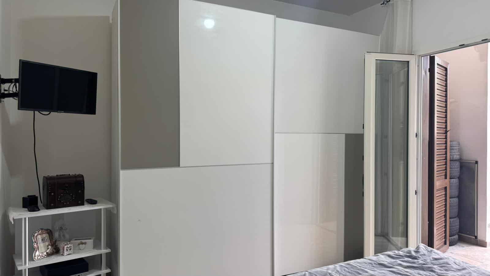 Armadio a muro bianco con ante scorrevoli in una camera da letto moderna; spazio ottimizzato per arredo casa e ambienti funzionali.