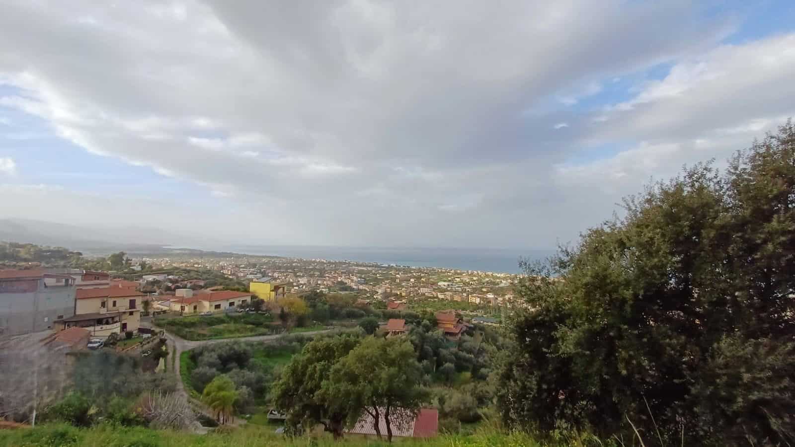 VISTA PANORAMICA DEL MARE E DELLE COLLINE DI UN'AREA RESIDENZIALE CON CASE E VERDEGGIANTI COLLINA IN UN'IMMOBILE NEXTCASA, ADATTA PER LA VENDITA O AFFITTO.