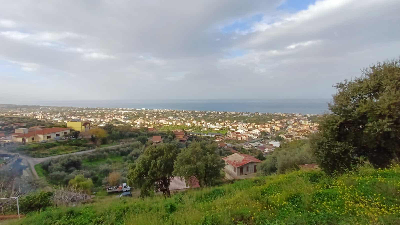 VISTA PANORAMICA DELLA COSTA E DEL PAESAGGIO URBANO DALLE COLLINE, con case, strade e vegetazione verde, vista sul mare, ideale per immobili residenziali e immobili di prestigio in Liguria.