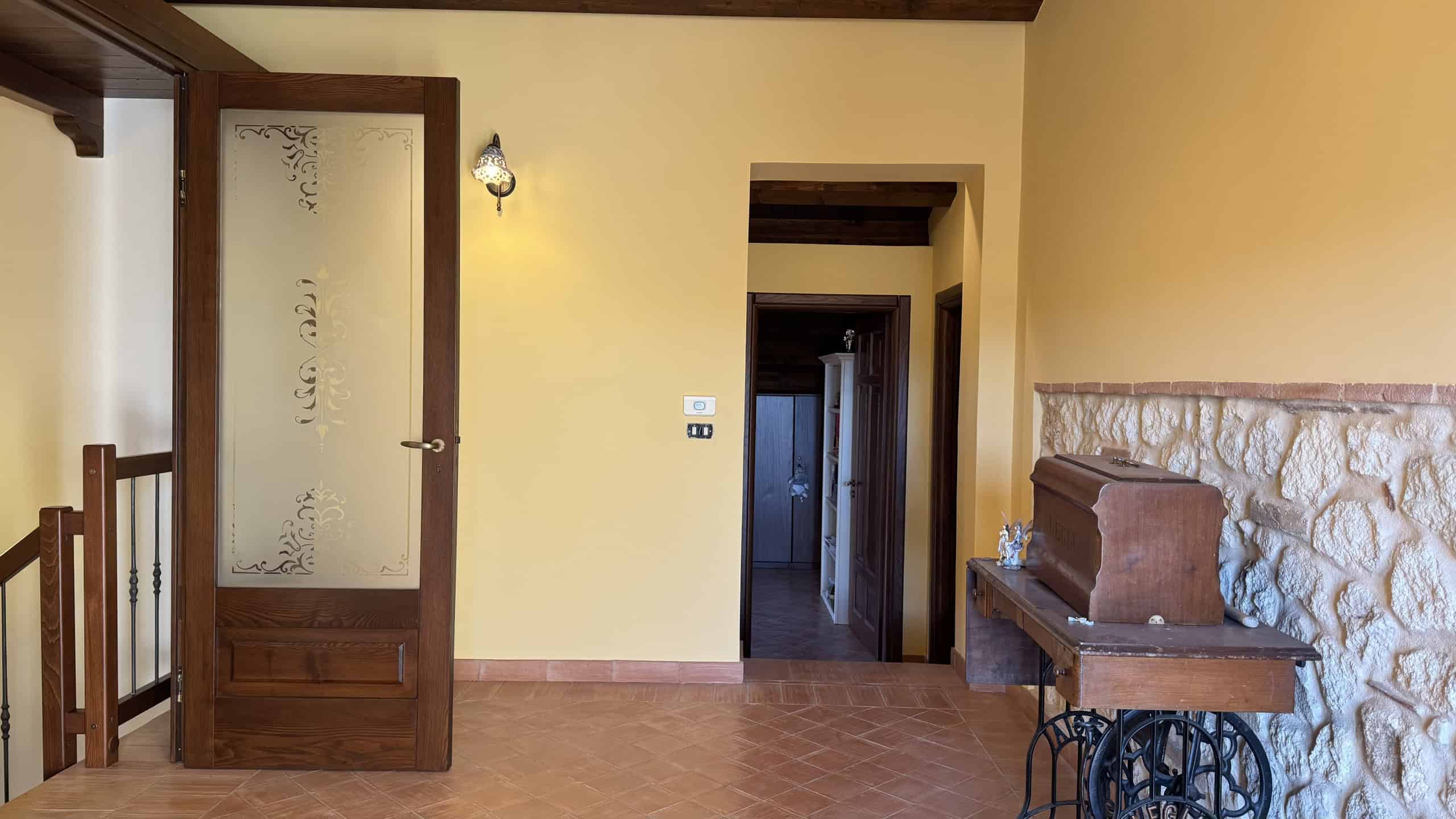 Porta in legno con decoro satinato, parete in pietra naturale, ambiente caldo e accogliente, arredamento rustico, dettaglio di design per case di charme.