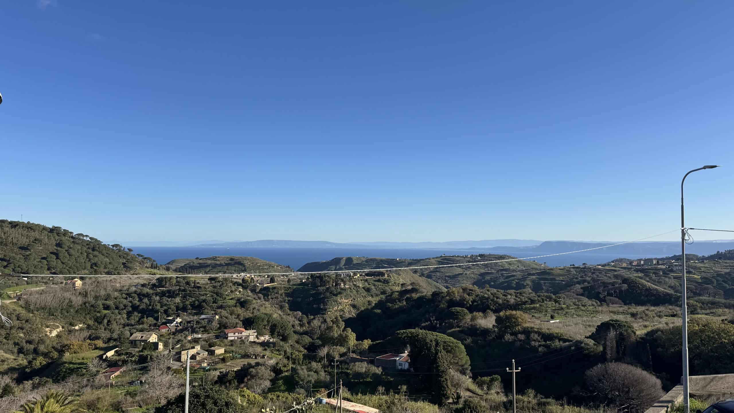 Vista panoramica delle colline e della costa, con cielo sereno e mare all'orizzonte, perfetta per immagini di immobili con paesaggi naturali e vista mare, ideale per il settore immobiliare NextCasa.