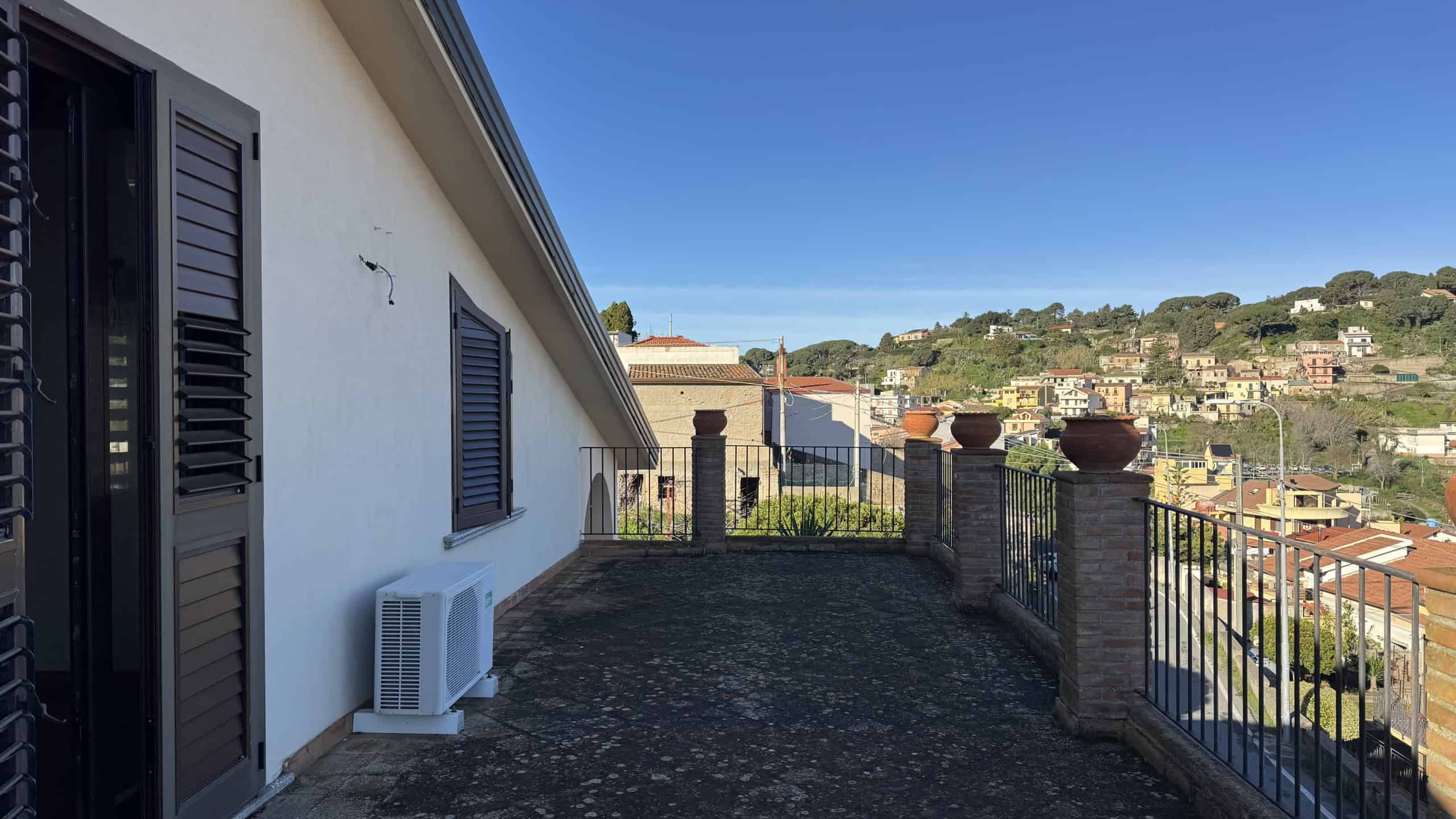 Vista panoramica su terrazza di casa con panorama urbano e colline, ideale per immobiliare e vendita con NextCasa, servizi immobiliari di qualità.