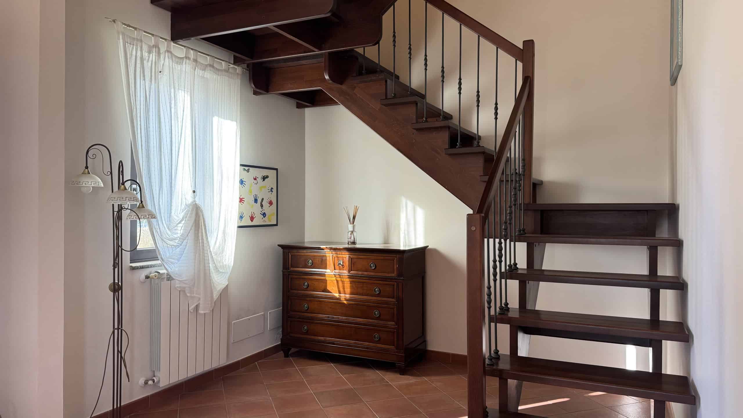 Scala in legno e ferro battuto, arredamento classico, ingresso elegante, casa di charme, mobilio in stile, soluzioni abitative, stile tradizionale, ambiente accogliente, design rustico, NextCasa Italia.
