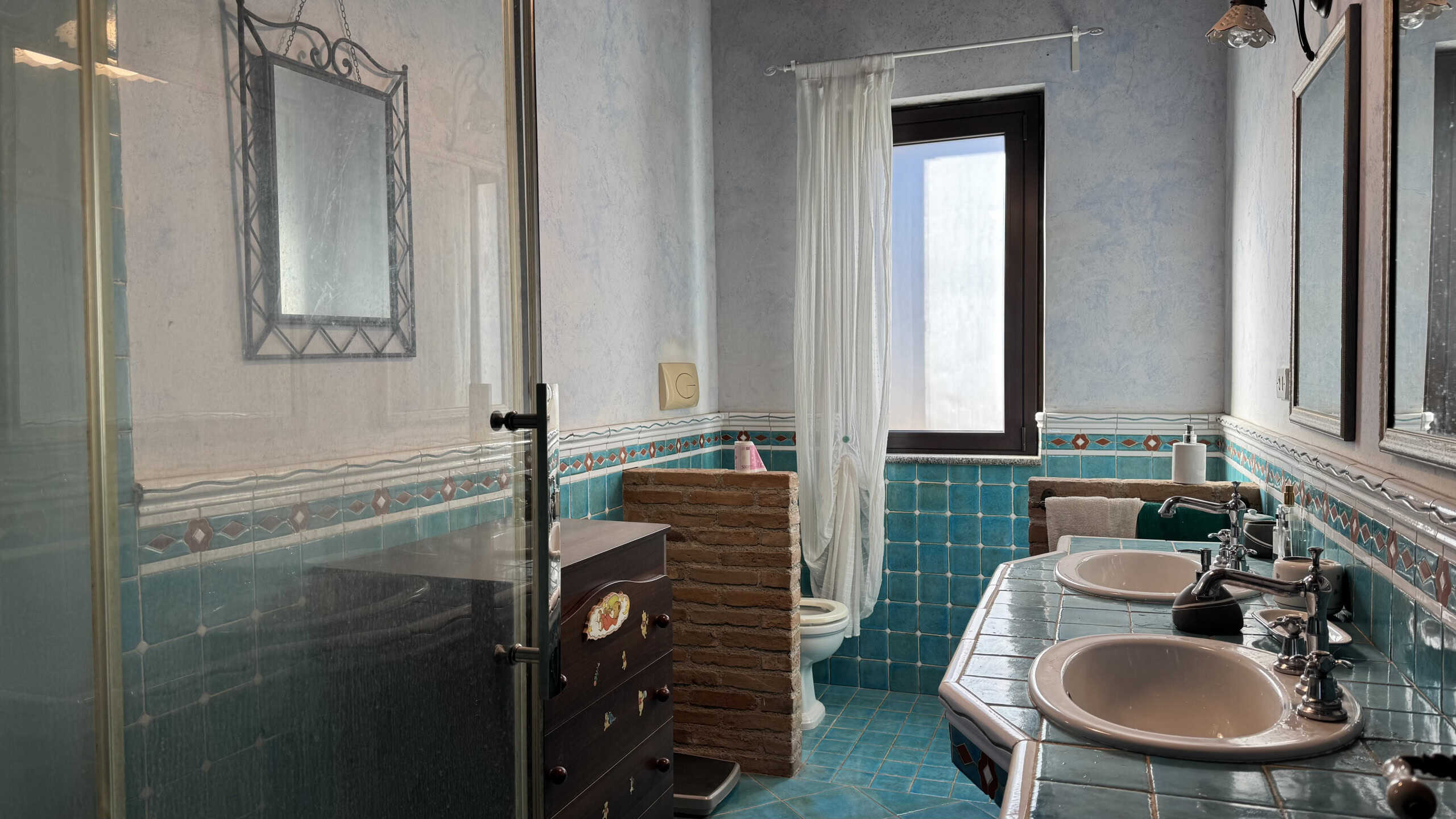 2 bagni moderni con piastrelle colorate, doppio lavabo e grande finestra luminosa, ideale per ristrutturazioni e interior design, offerte da NextCasa.