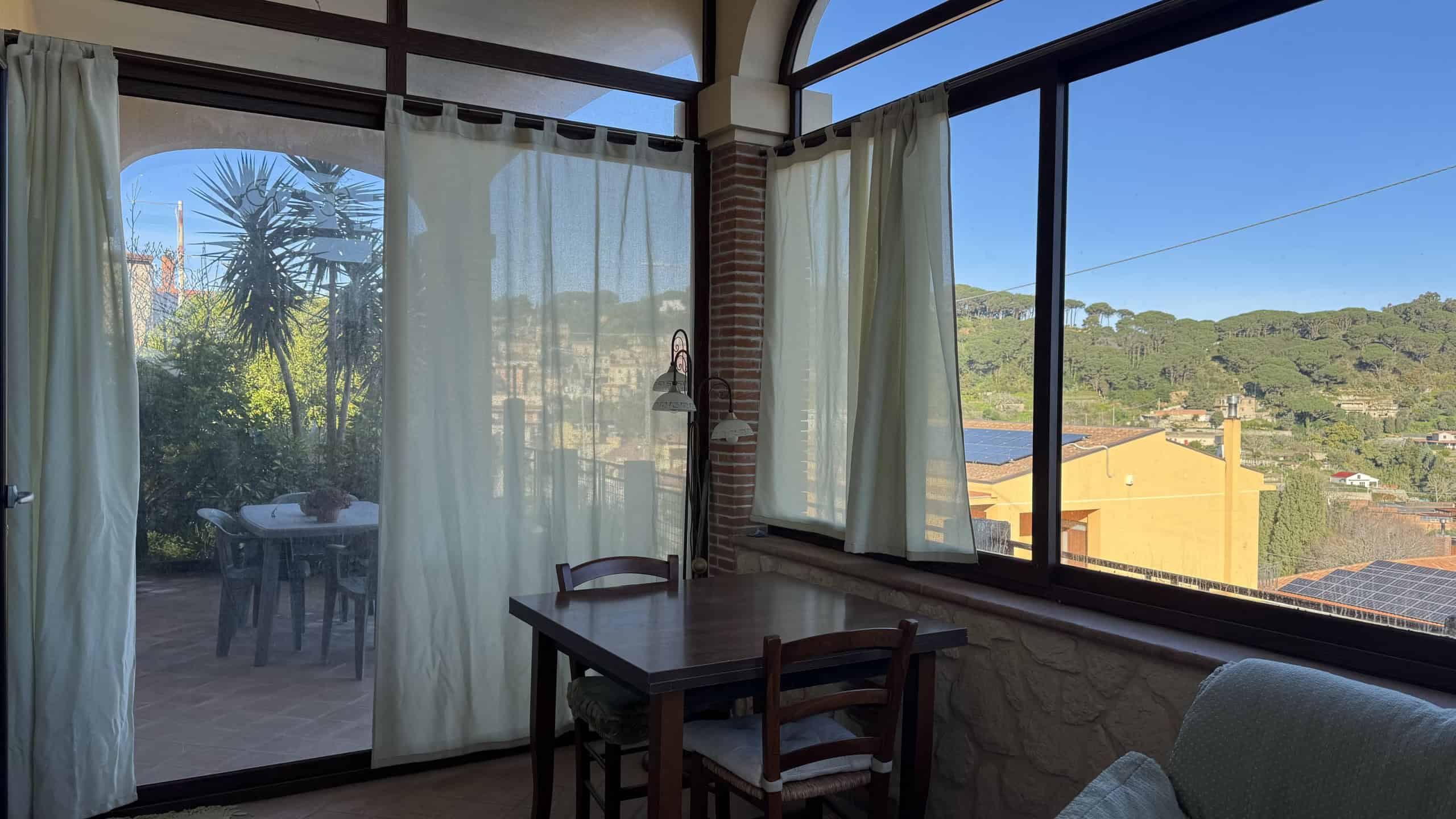 Vista panoramica sulla natura e le colline dalla finestra soleggiata di una casa a NextCasa, perfetta per vivere in tranquillità e comfort immersi nel verde.
