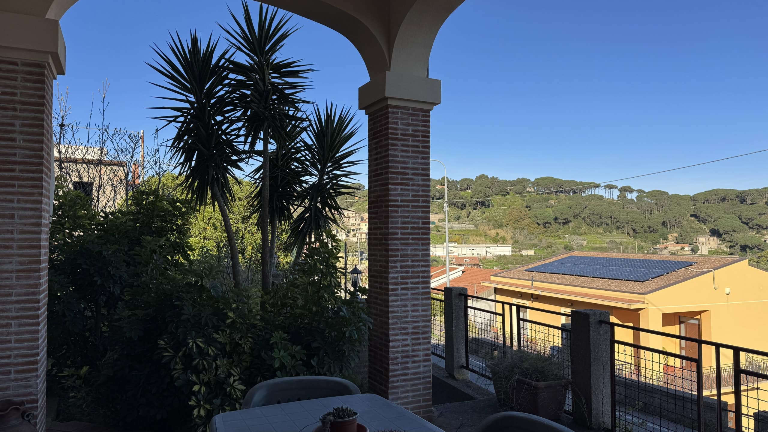 Veranda con vista sulle colline con pannelli solari sul tetto e giardino con piante tropicali, atmosfera rilassante e panorama panoramico, ideale per vivere all'aperto e godersi la natura.