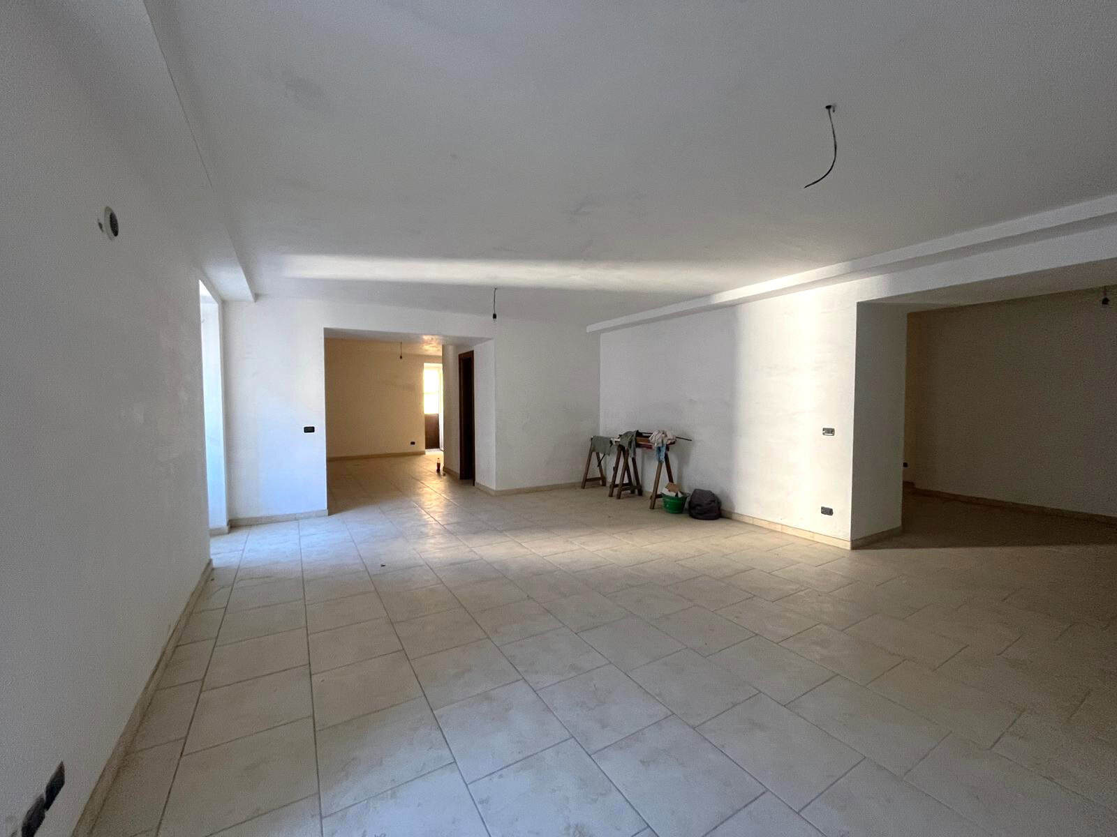 Interno di appartamento in fase di ristrutturazione con pareti bianche e pavimento in piastrelle, pronto per personalizzazione.
