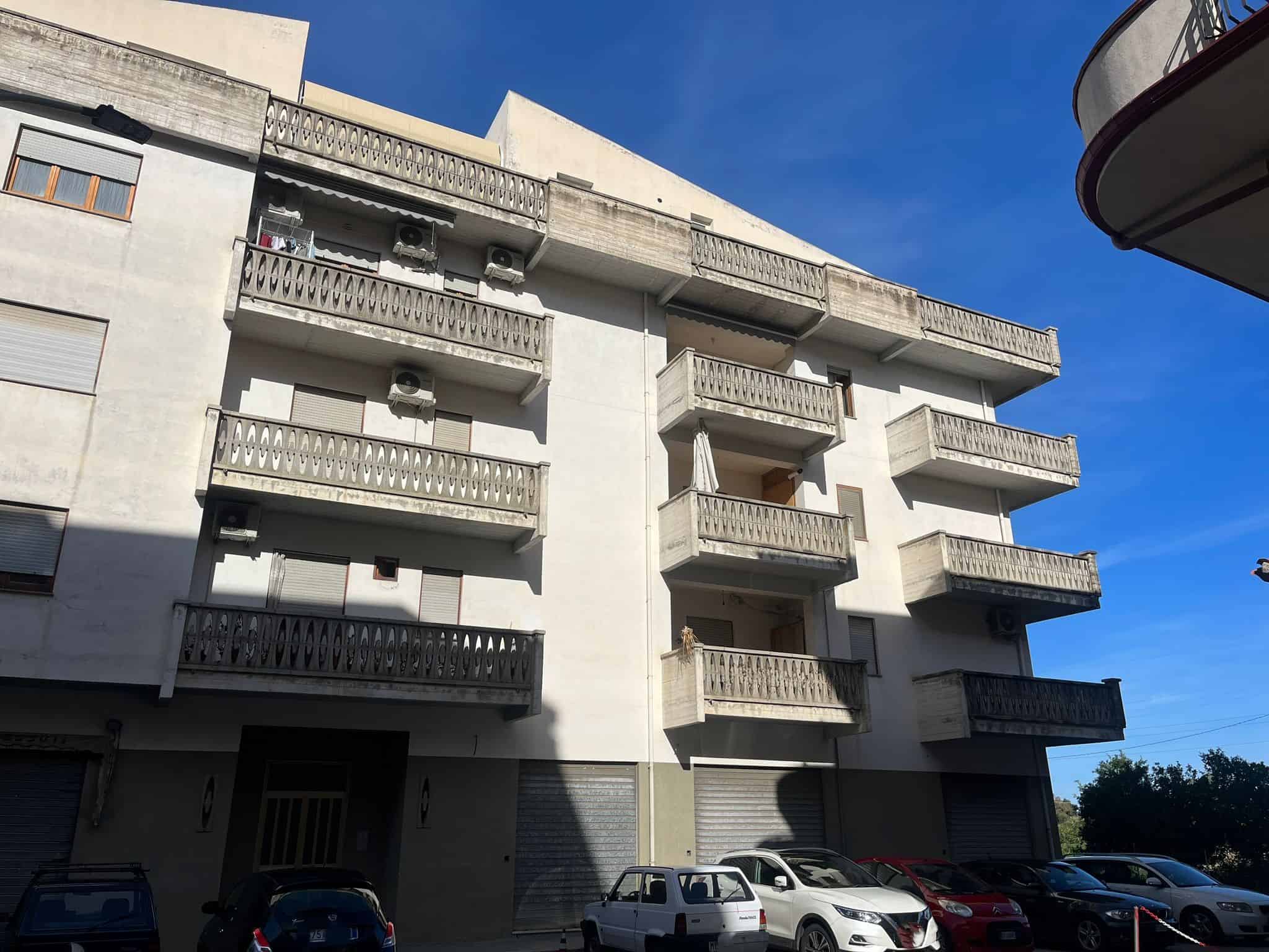 Stabile residenziale con balconi in cemento e aria condizionata, situato in zona urbana, con parcheggio e ambiente urbano e tranquillo, in stile moderno.