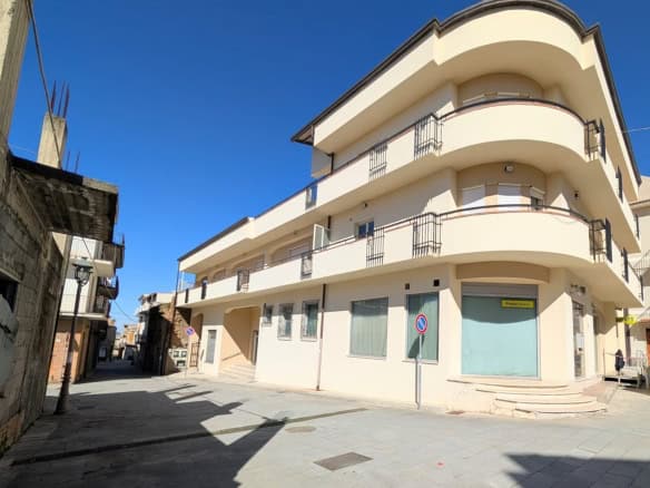 Villa moderna con balconi su strada principale, edificio residenziale di design contemporaneo situato in un'area urbana soleggiata, con ampie finestre e spazi esterni per vivere all'aperto.