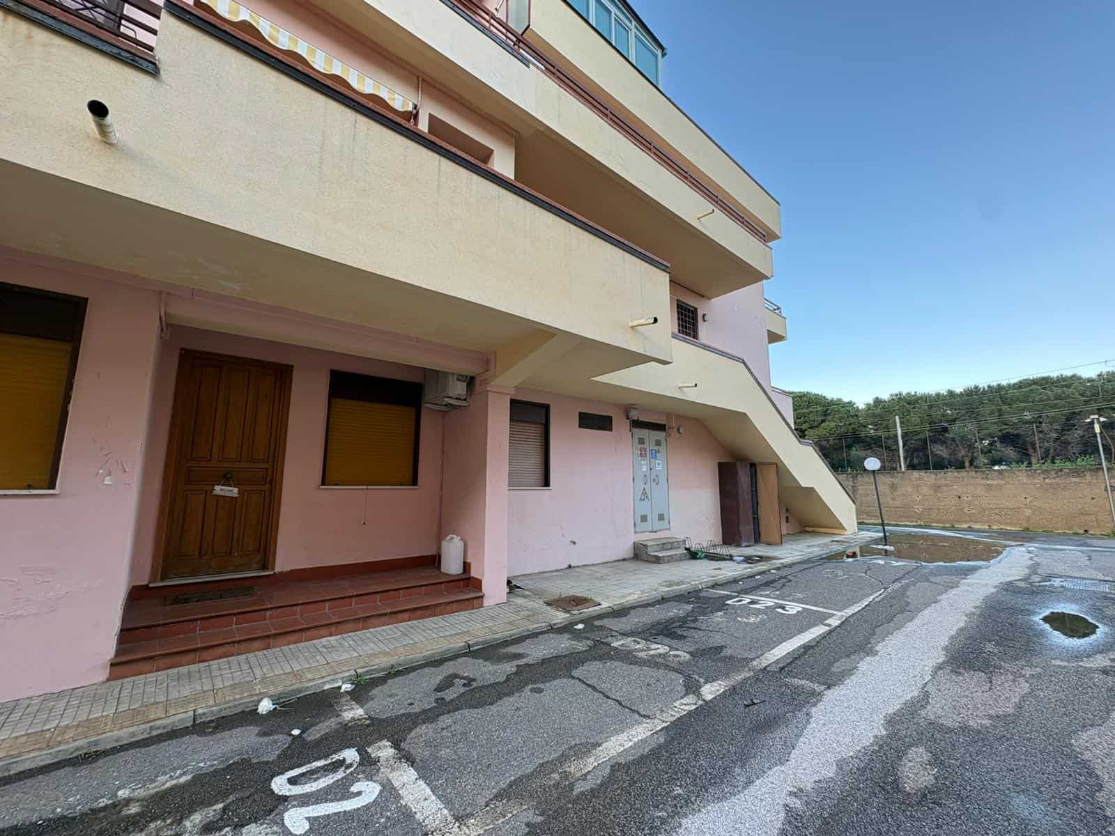 Porte d'ingresso e ingresso di un edificio residenziale con parcheggio esterno, vista frontale, in una giornata soleggiata.