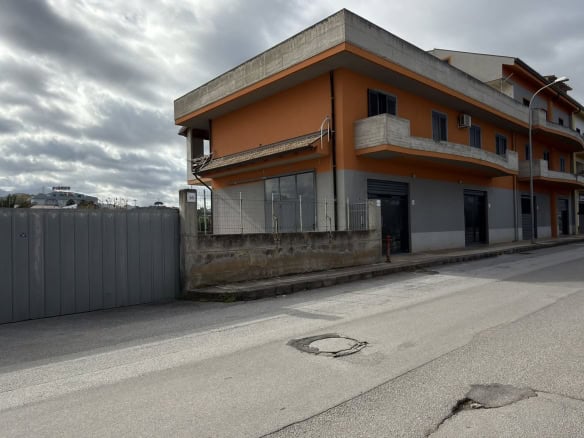 Ampio edificio residenziale con balconi e facciata moderna, situato in una zona urbana con strada asfaltata e cielo nuvoloso, ideale per investimenti immobiliari o abitazioni familiari.