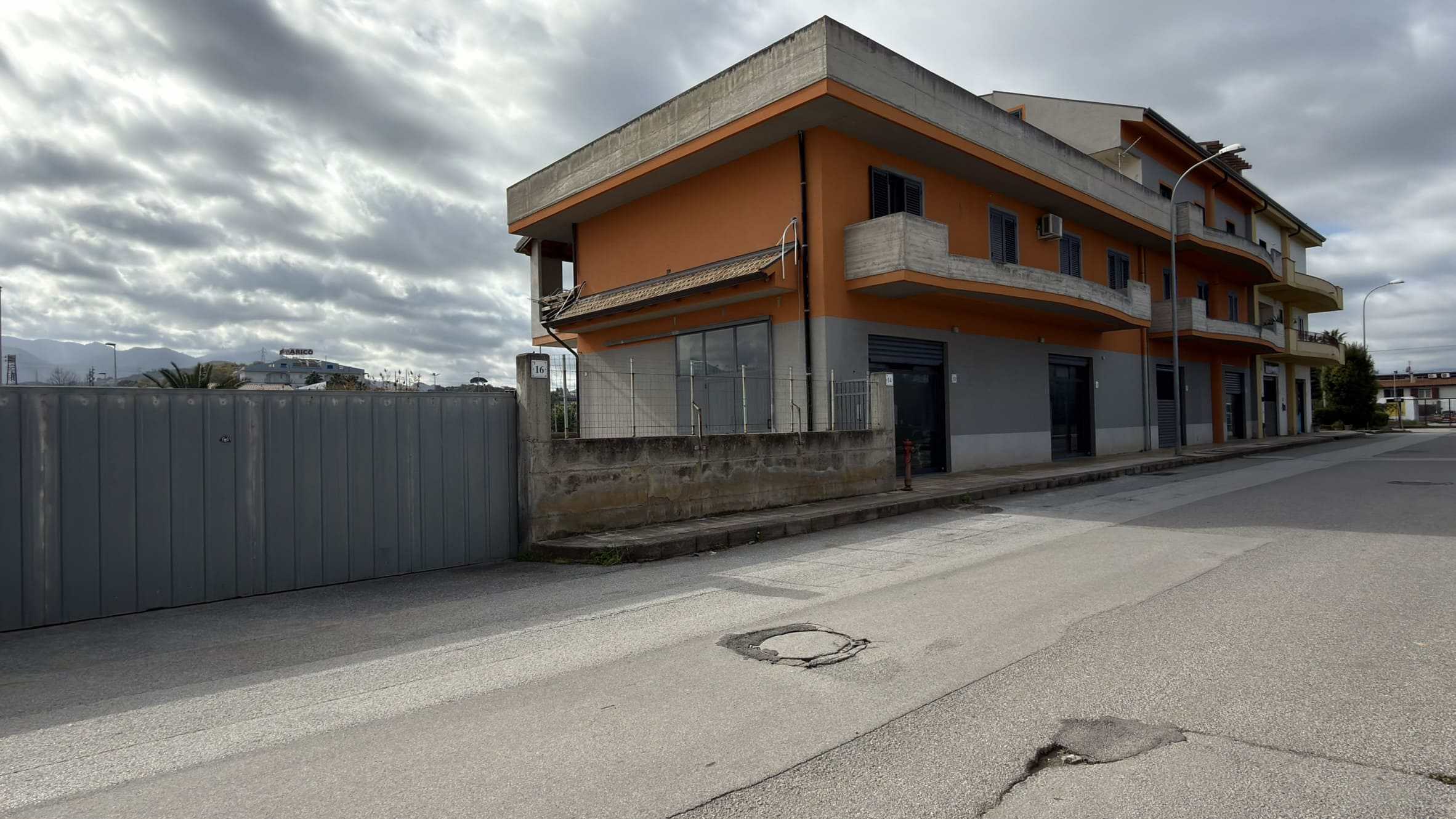 1 Ampio edificio residenziale con balconi e facciata moderna, situato in una zona urbana con strada asfaltata e cielo nuvoloso, ideale per investimenti immobiliari o abitazioni familiari.