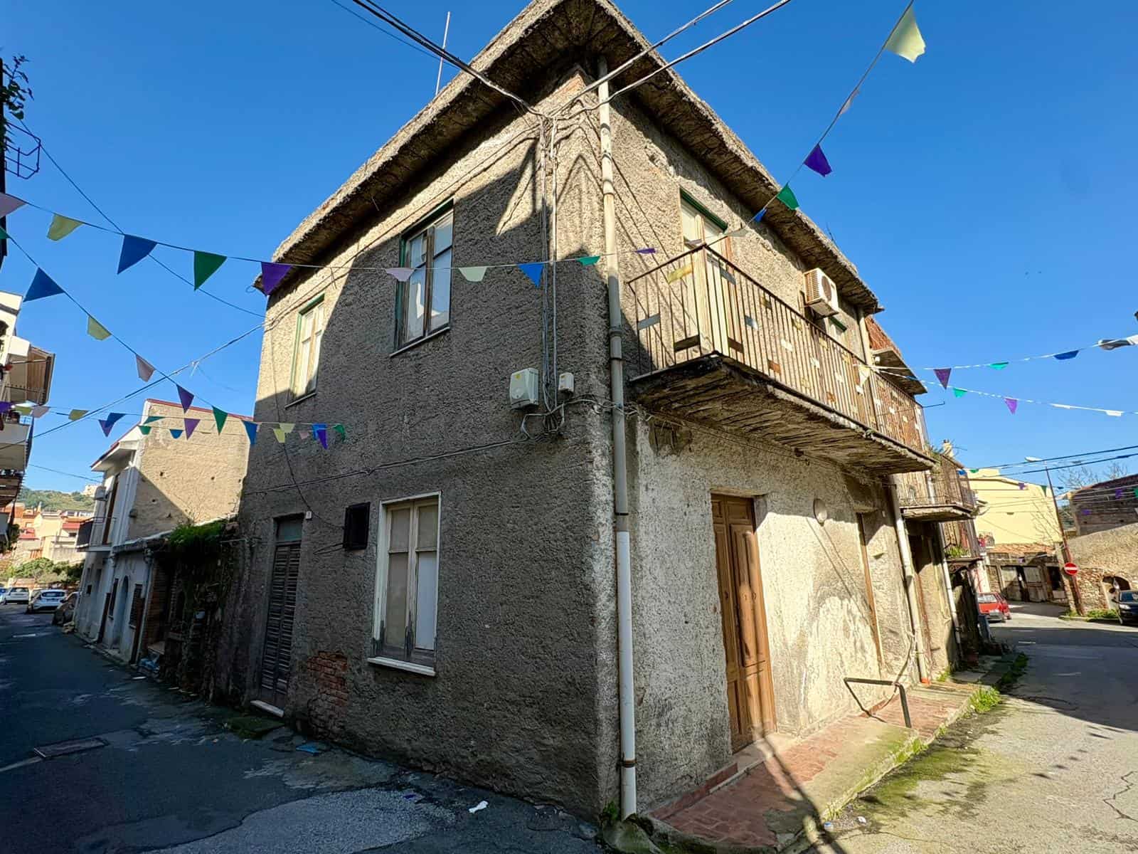 Casa indipendente in pietra con balcone e decorazioni di bandiere colorate, situata in zona urbana soleggiata.