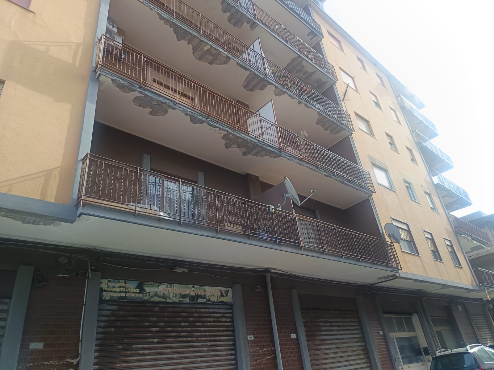 Balcone di un appartamento in un edificio residenziale con ringhiere in metallo e tende parasole, vista dall'esterno.