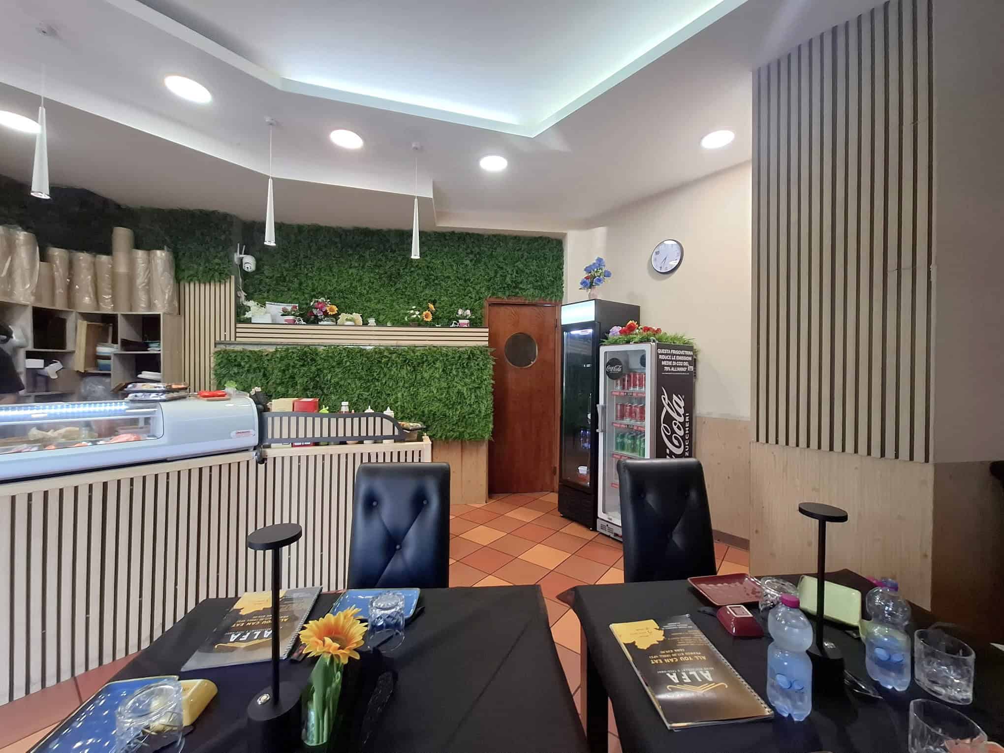 Aria moderna e accogliente di un bar o caffetteria con arredi eleganti, pareti verdi e illuminazione soffusa, ideale per momenti di relax e socializzazione.