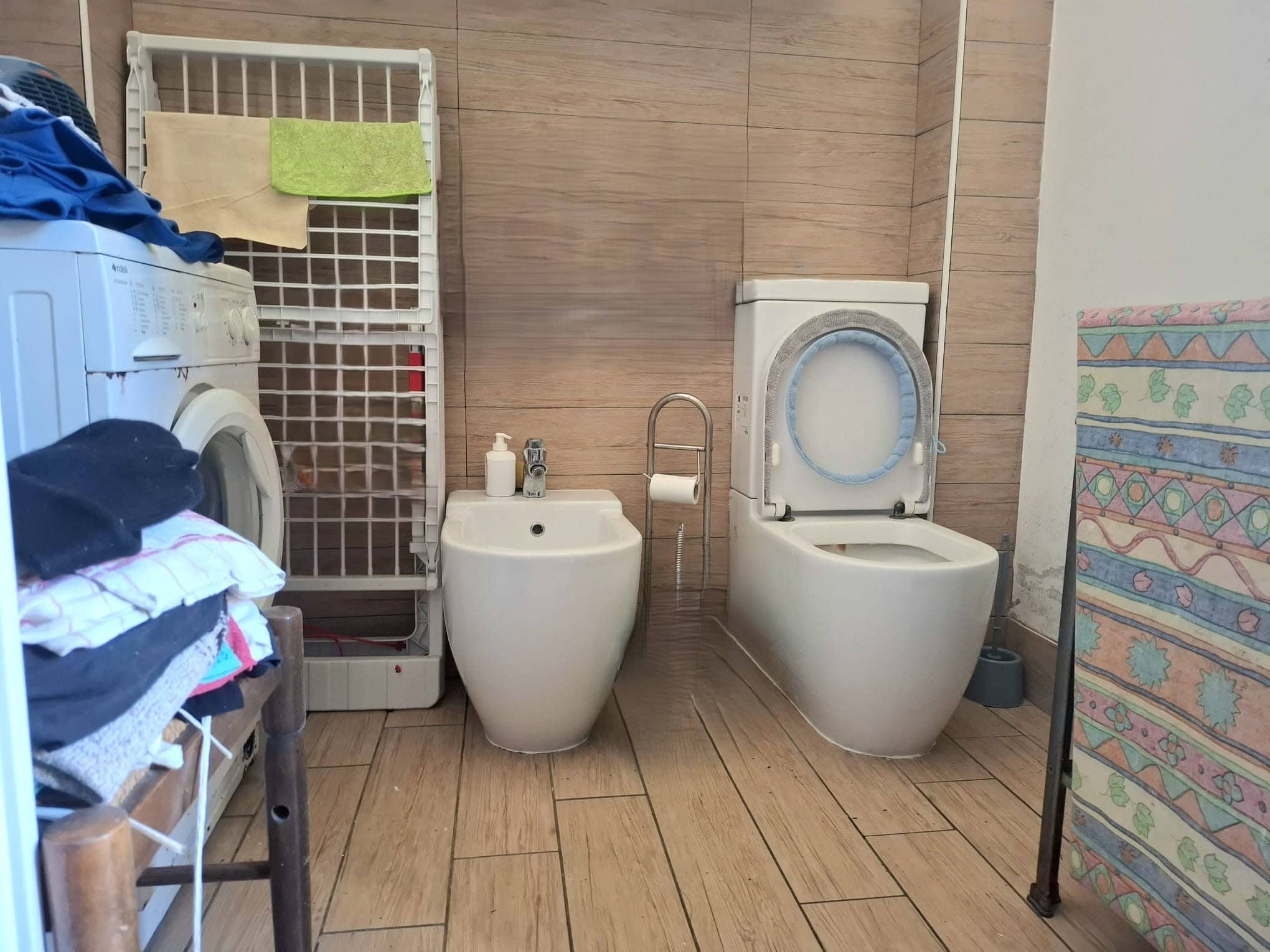 Lavatrice e asciugatrice in un bagno con pareti in legno e pavimento in piastrelle di ceramica, spazio funzionale per lavanderia domestica.