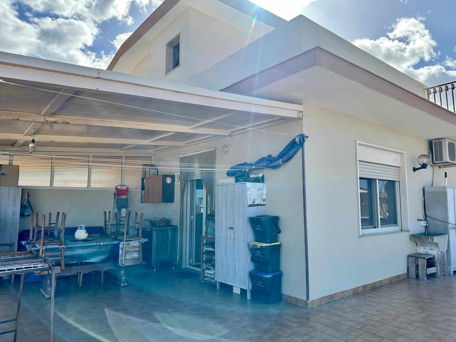 Ampia terrazza esterna con area coperta, arredi da giardino e spazio per il relax, ideale per vivere all'aperto durante le belle giornate.