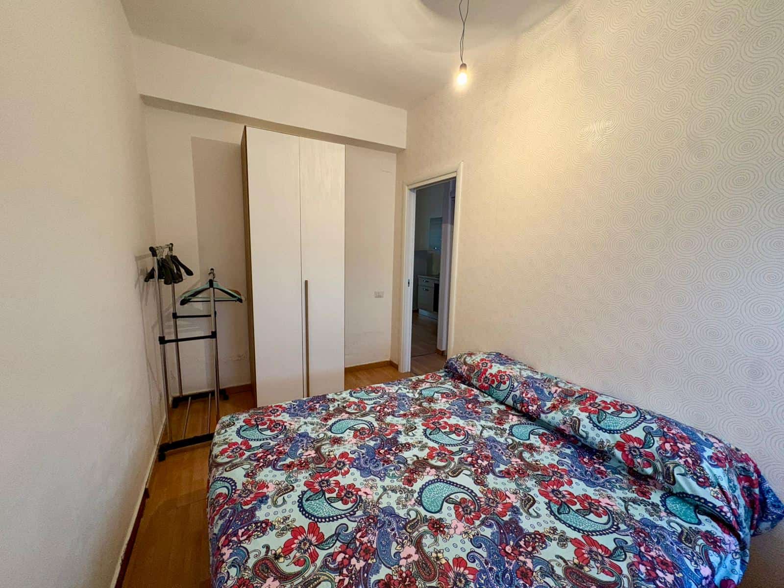 Appartamento con camera da letto arredata, armadio e parete decorativa, ideale per affitti brevi o residenziali, situato in zona tranquilla e ben servita.