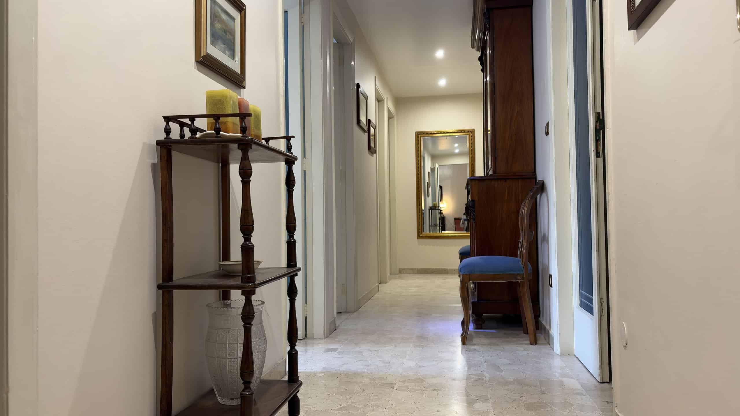 Spazio di ingresso elegante con mobili classici, specchi e decorazioni artistiche, ideale per un ambiente accogliente e raffinato in una casa di lusso.