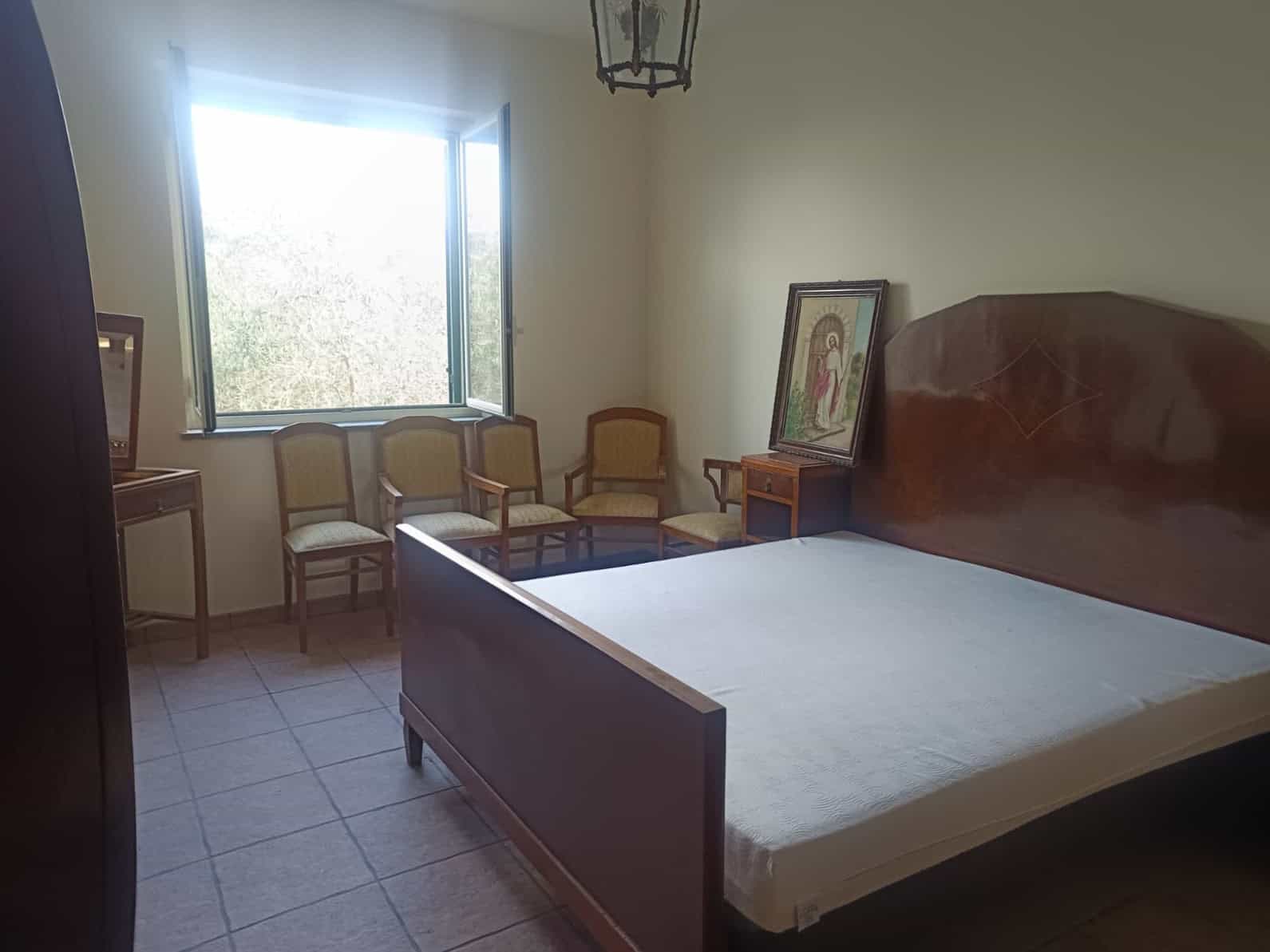 Letto matrimoniale in camera con finestra luminosa e sedie d'epoca, ideale per affitti brevi o soggiorni rilassanti, con arredi classici e atmosfera accogliente.