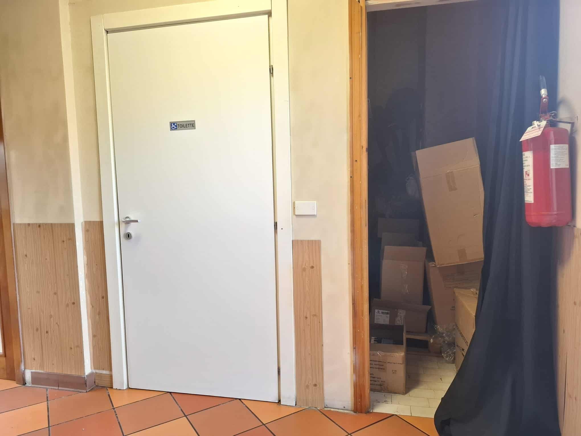 Pannello di uscita di sicurezza in un ambiente interno con pareti in legno e pavimento in piastrelle di ceramica.