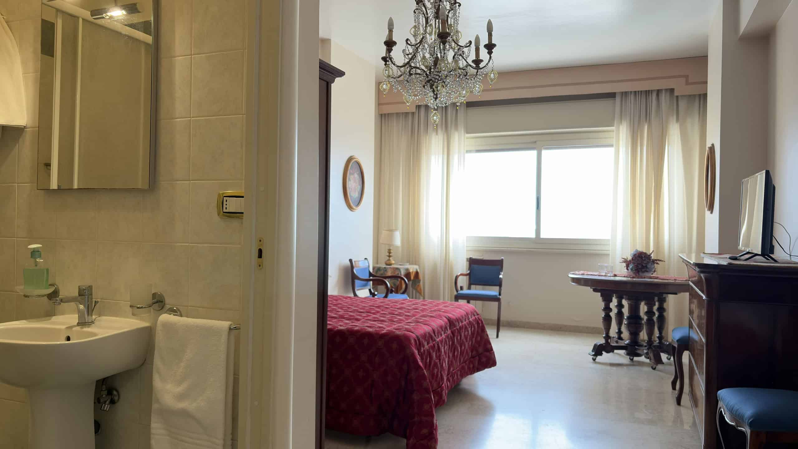 Lavabo e bagno in un ambiente domestico con pareti beige, specchio e asciugamano bianco.