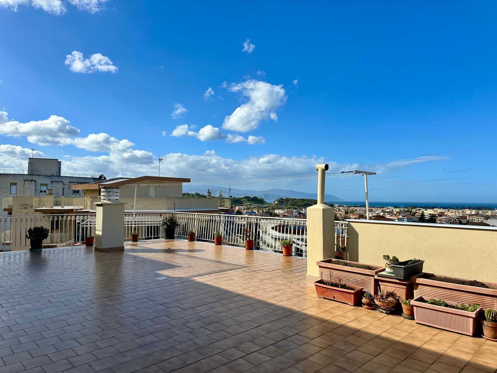 Vista panoramica di un terrazzo con piante e vista mare, ideale per immobili residenziali in vendita o affitto a NextCasa, agenzia immobiliare specializzata in proprietà di lusso in Italia.