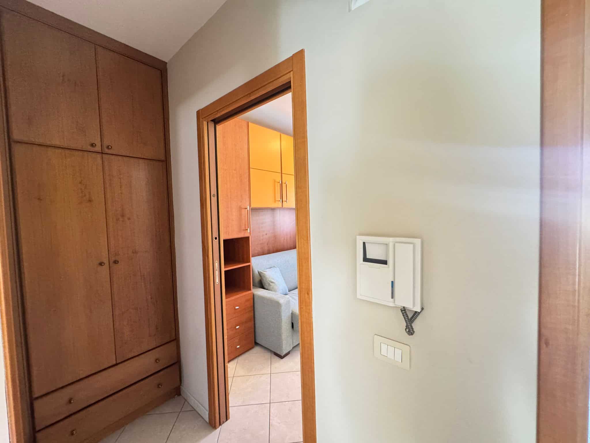 Armadio in legno con ante a battente e cassetti, vista dall'ingresso di una camera da letto.