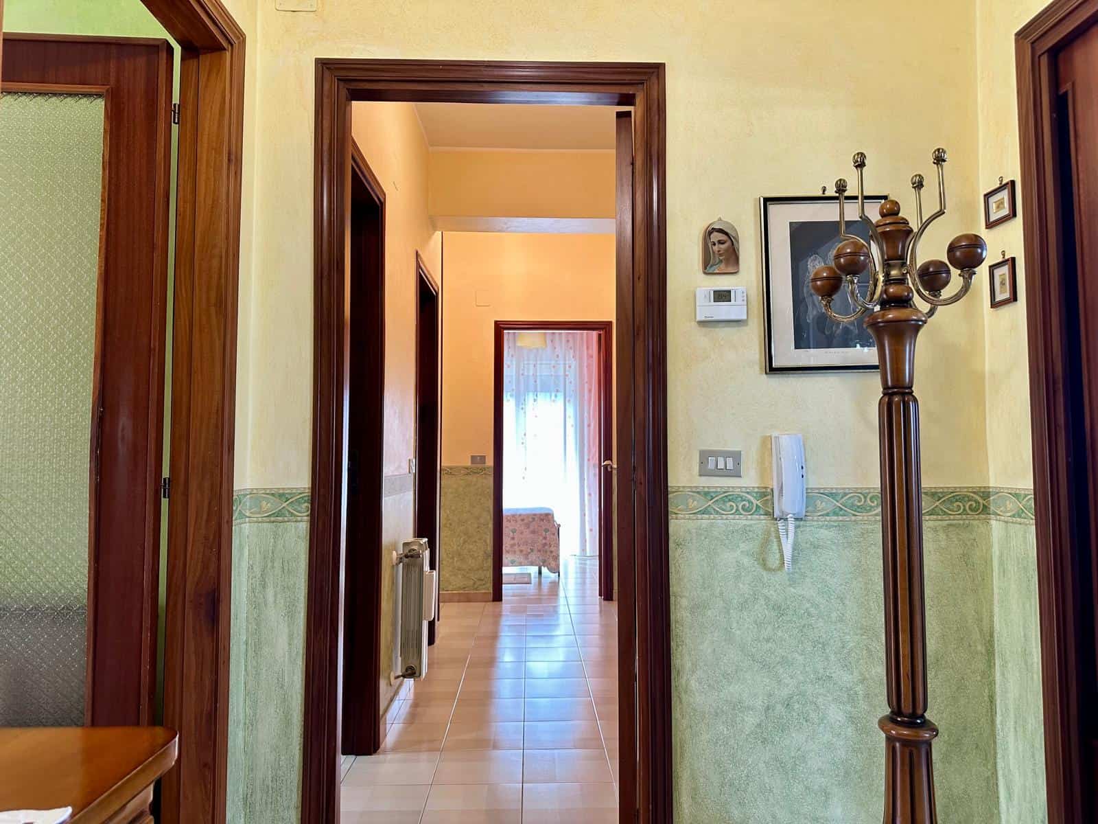 Interno di un appartamento con ingresso, pareti color crema e dettagli in legno, arredamento funzionale e atmosfera accogliente, ideale per vivere in comfort.