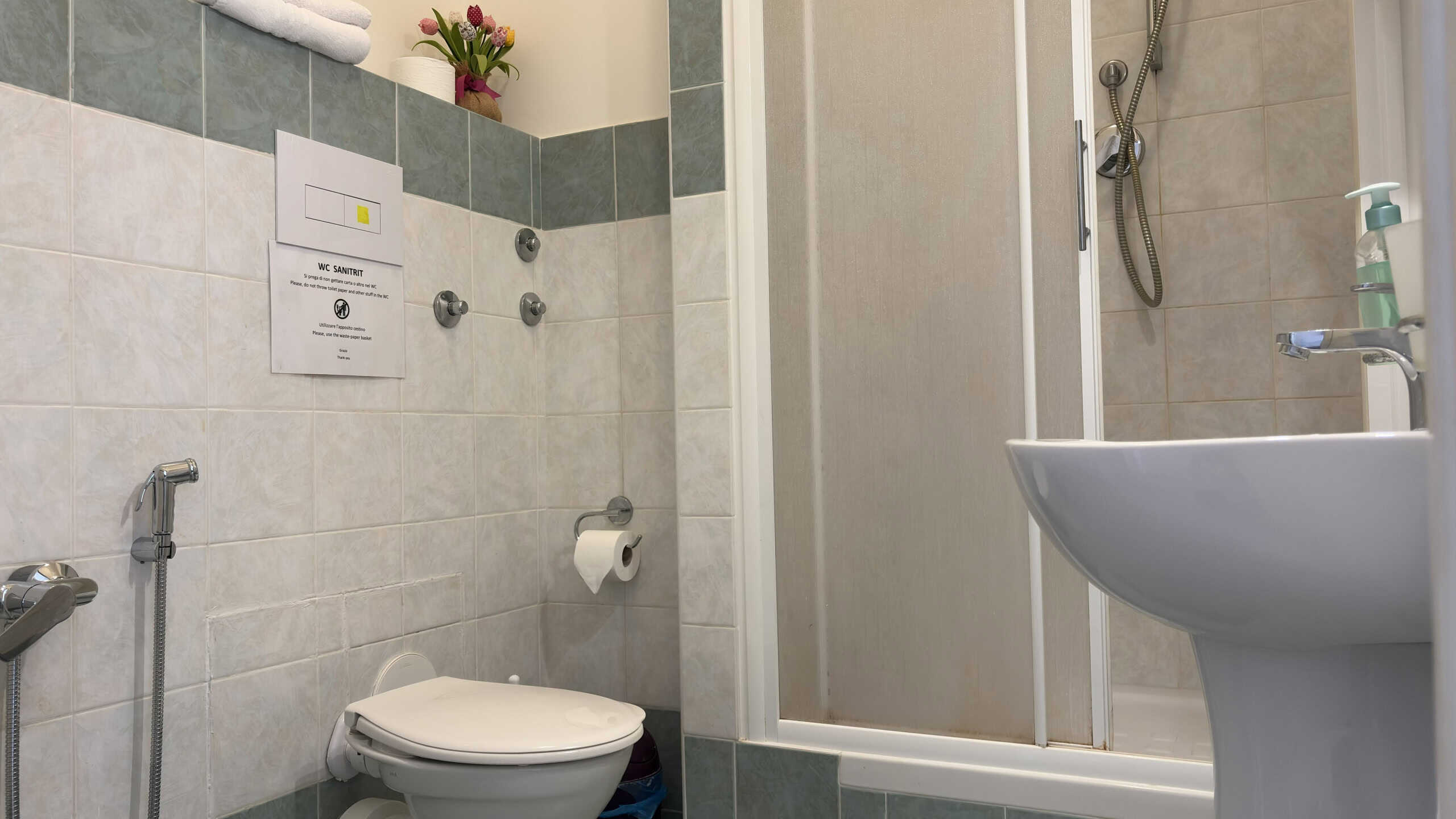 Spazio bagno moderno con doccia, lavabo e accessori essenziali, ideale per appartamenti e case private, evidenziando funzionalità e design contemporaneo.