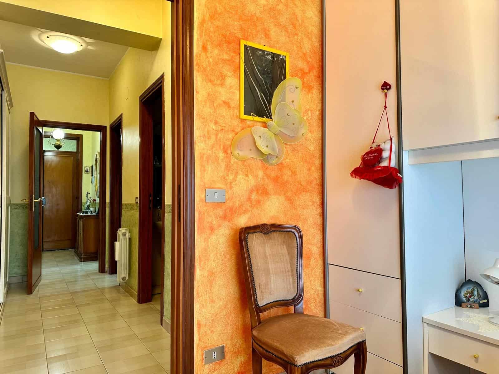 Pannello decorativo con farfalla in stile moderno, arredamento accogliente e colorato in un ingresso di casa, con mobili funzionali e dettagli decorativi vivaci.