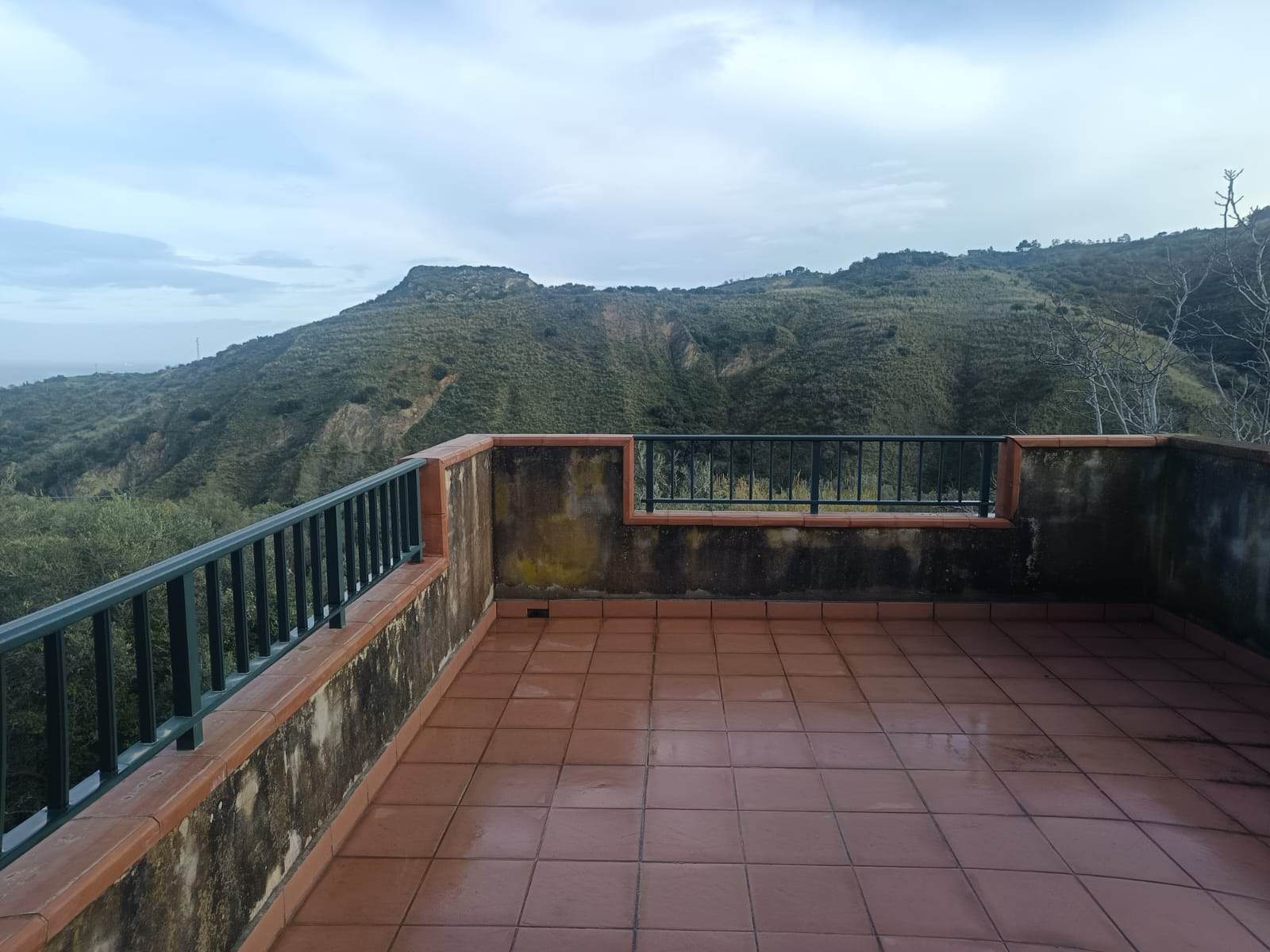Balcone con vista panoramica su colline verdi e cielo nuvoloso, ideale per relax e contemplazione della natura.
