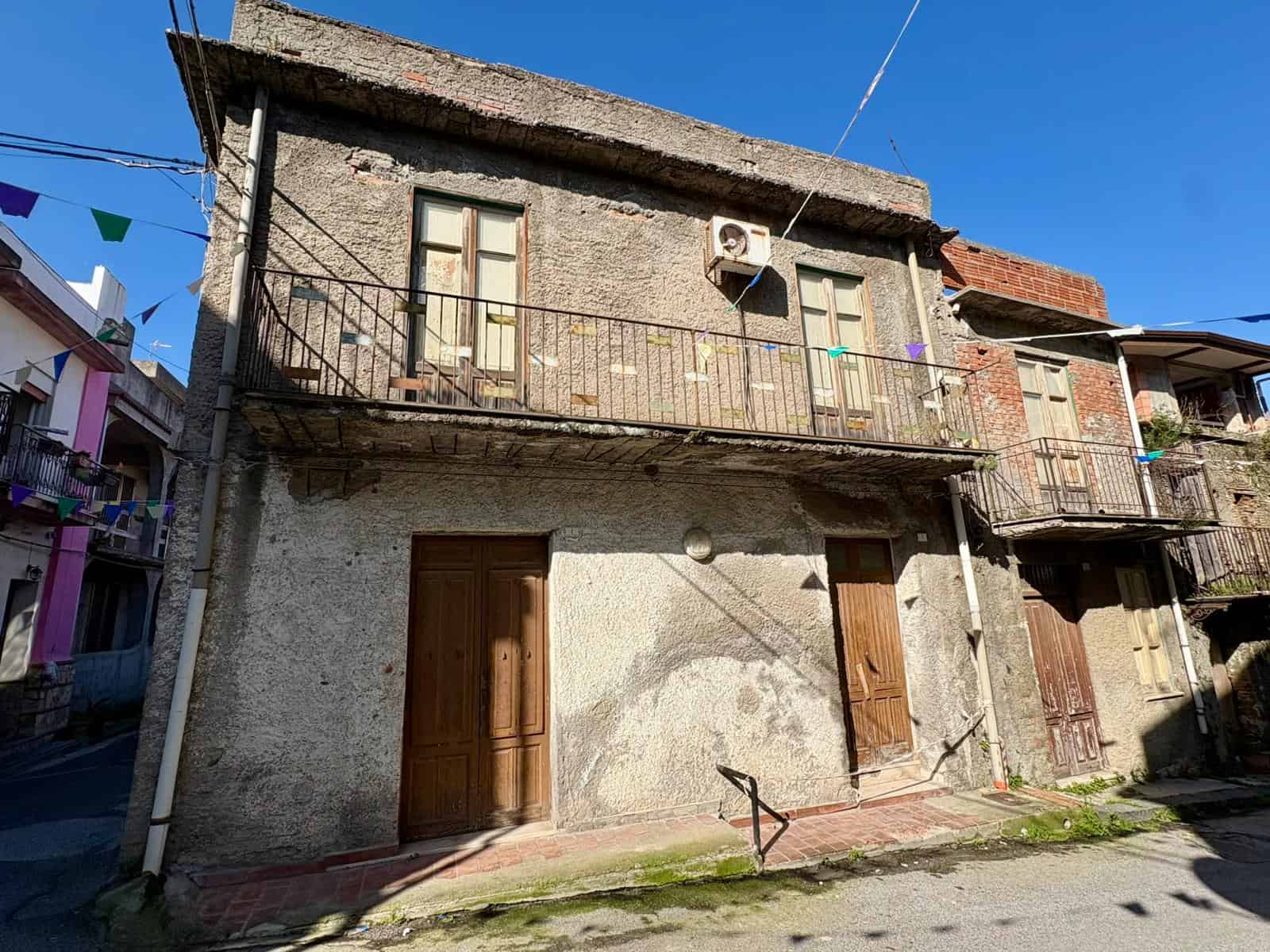 2 Edificio residenziale storico con balcone in ferro battuto e facciata in pietra, situato in zona urbana di NextCasa, perfetto per investimenti immobiliari e ristrutturazioni.
