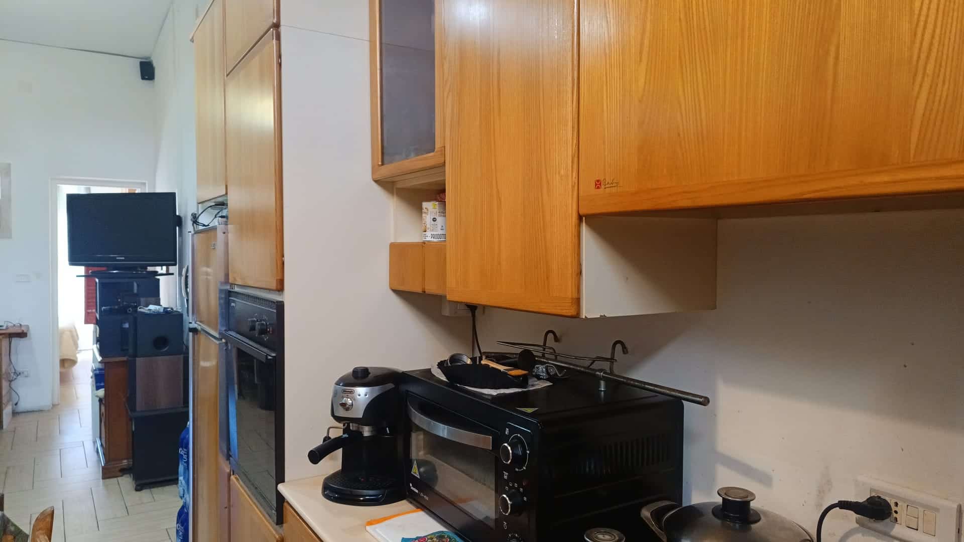 Ampia cucina con mobili in legno, elettrodomestici moderni e spazio per la preparazione dei pasti, ideale per vivere in comfort e stile.